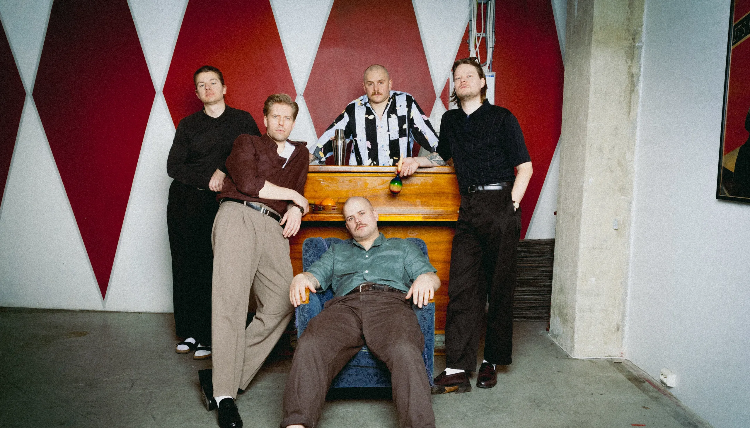 Fem unge menn står henslengt rundt et piano.