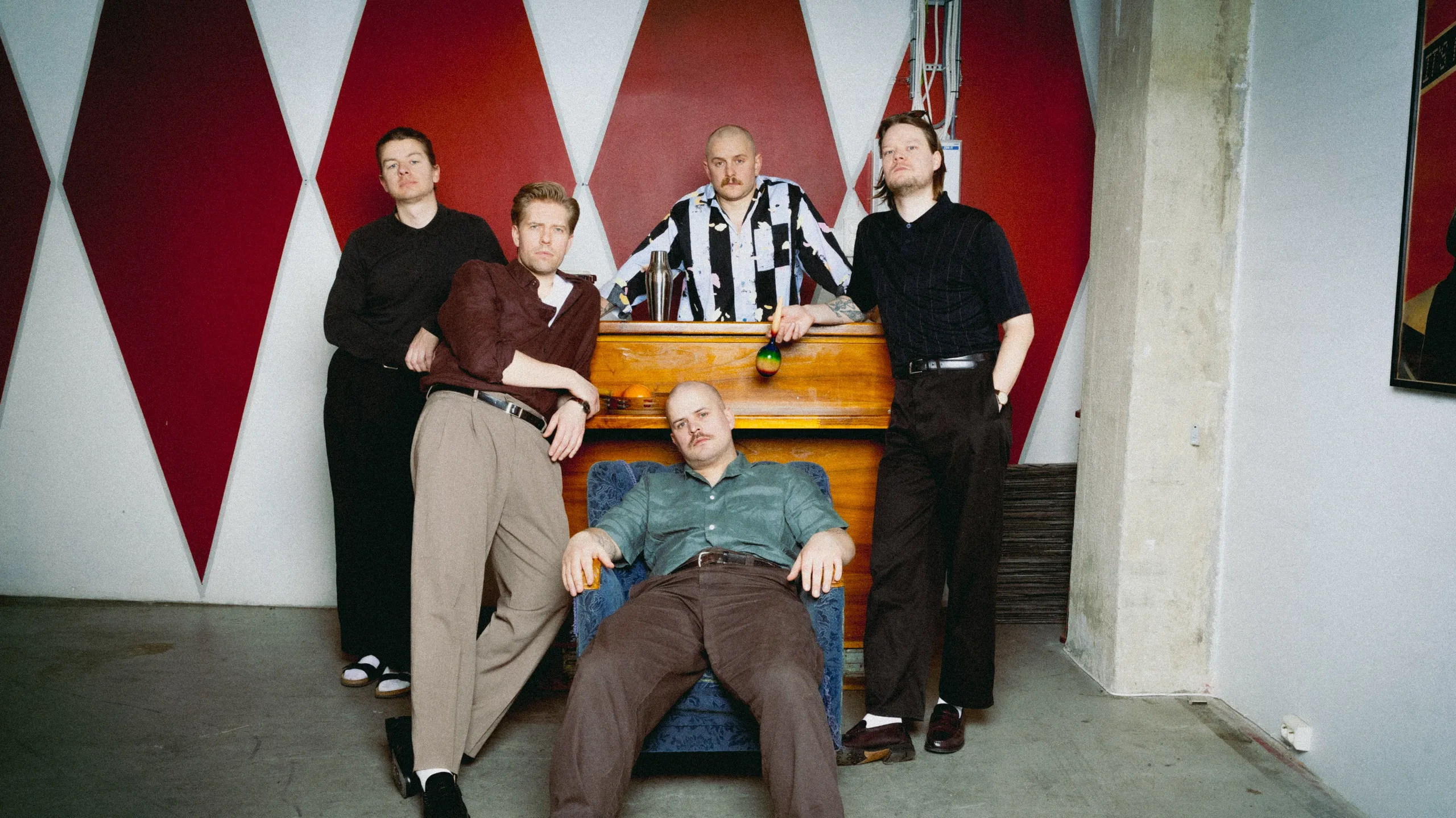 Fem unge menn står henslengt rundt et piano.