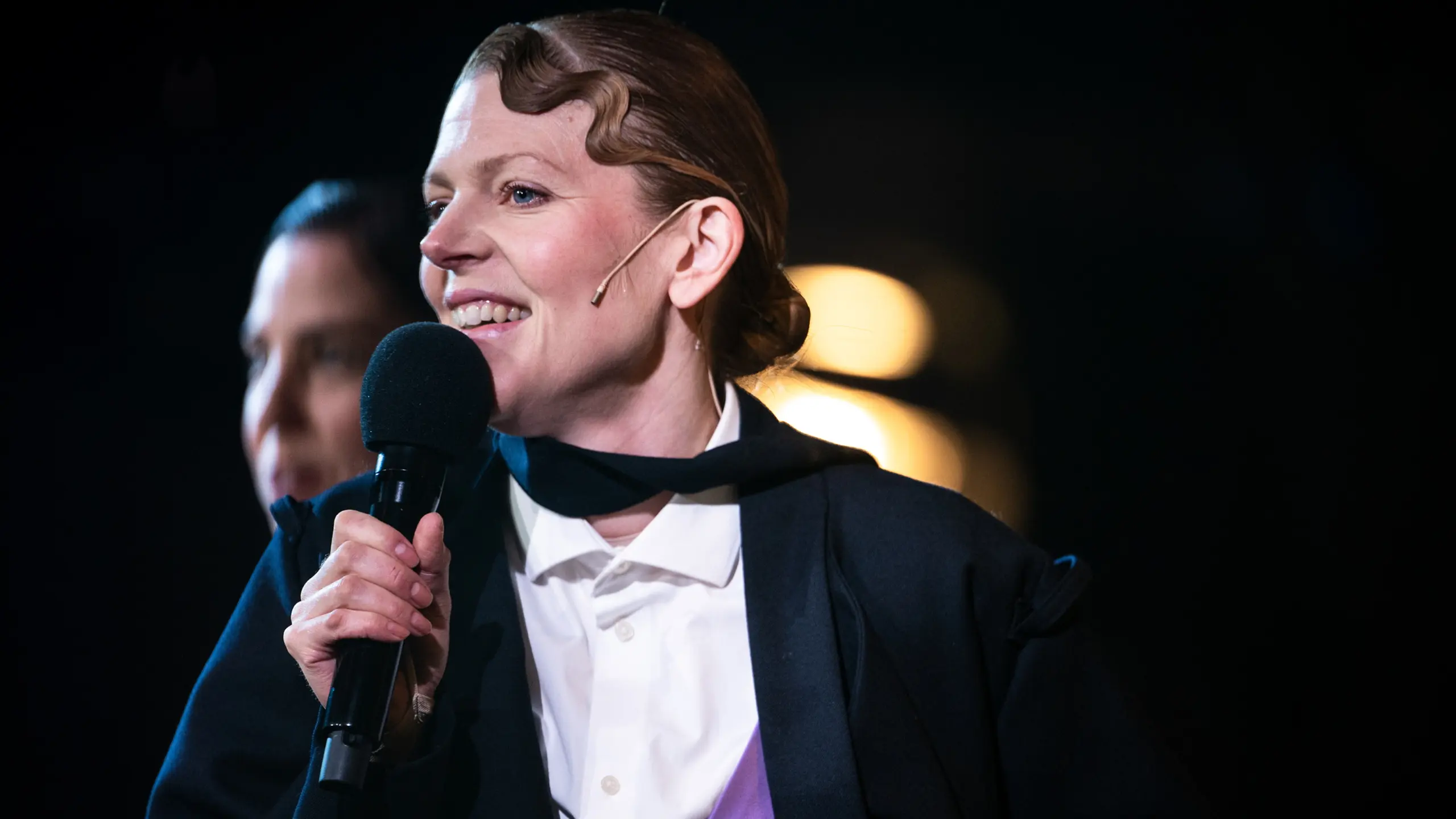 Smilende kvinne snakker i mikrofon