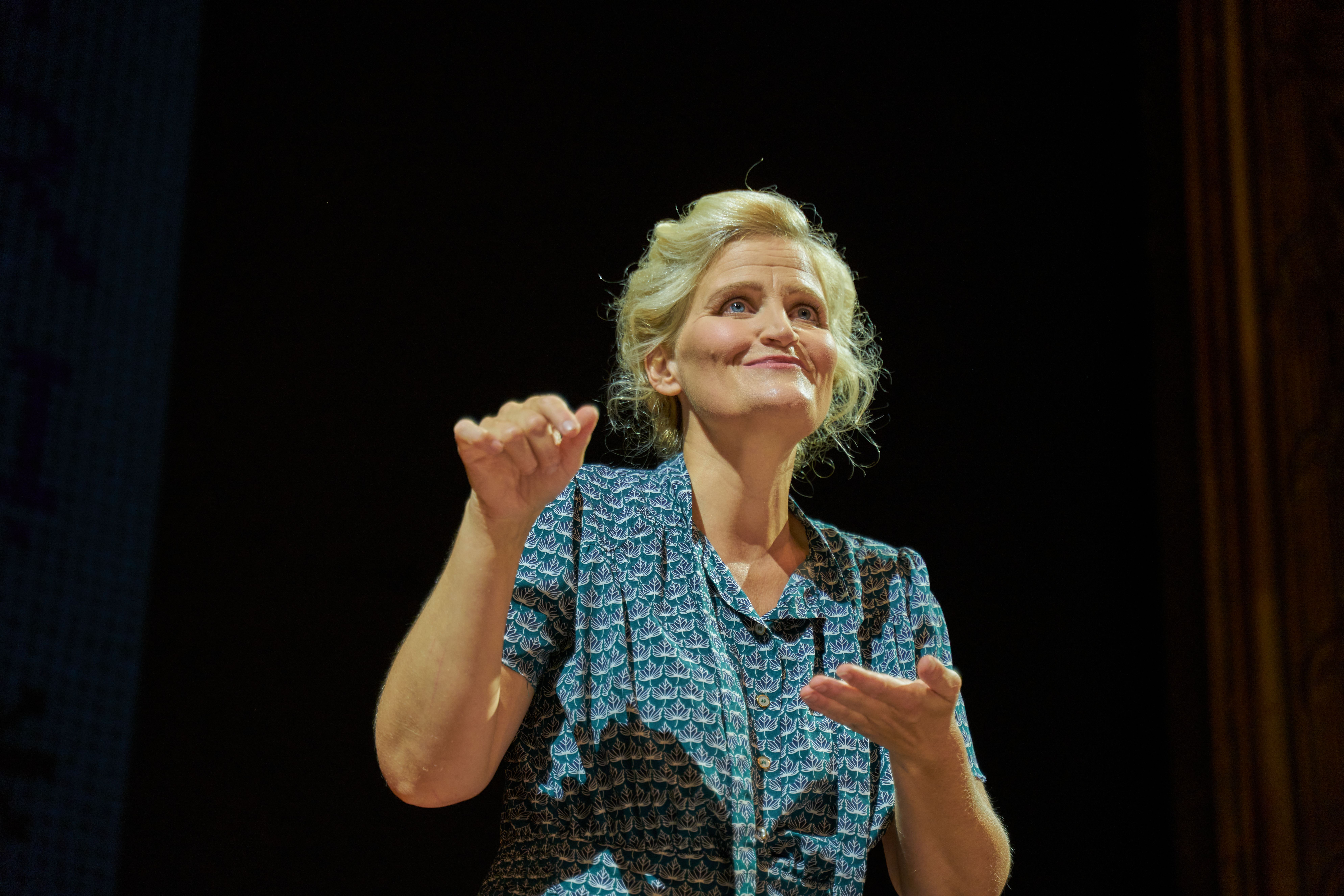 Kvinne gestikulerer og smiler på en scene