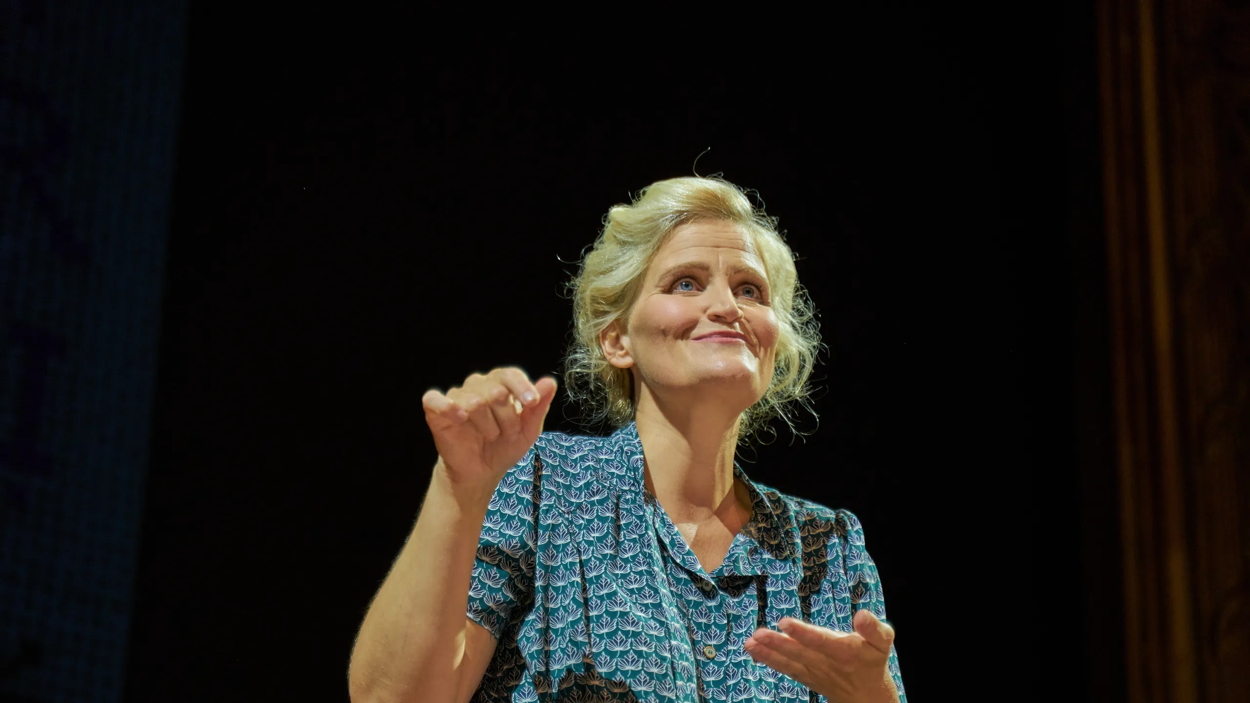 Kvinne gestikulerer og smiler på en scene