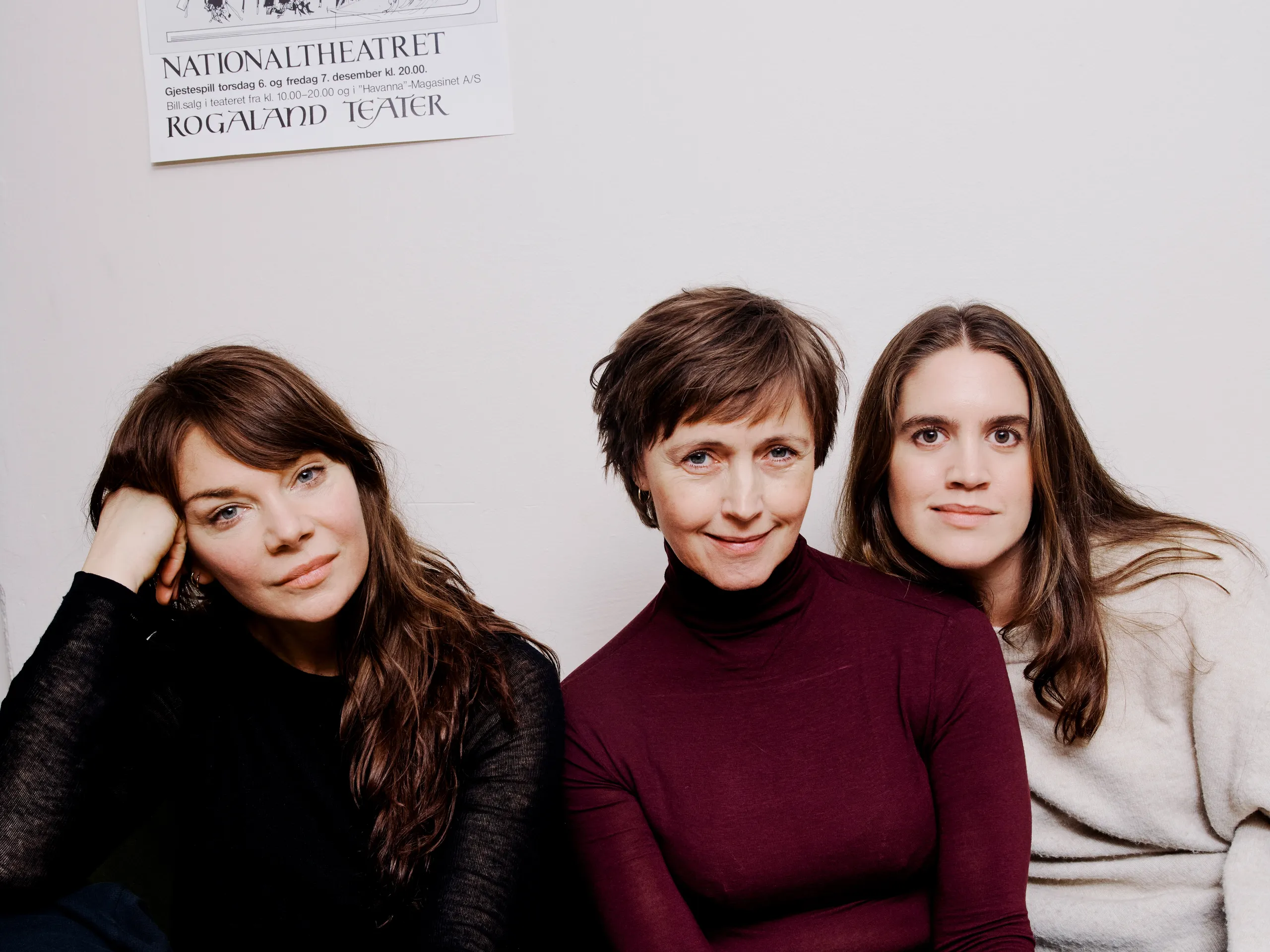 Tre kvinner sitter i en grønn sofa mot en hvit vegg.