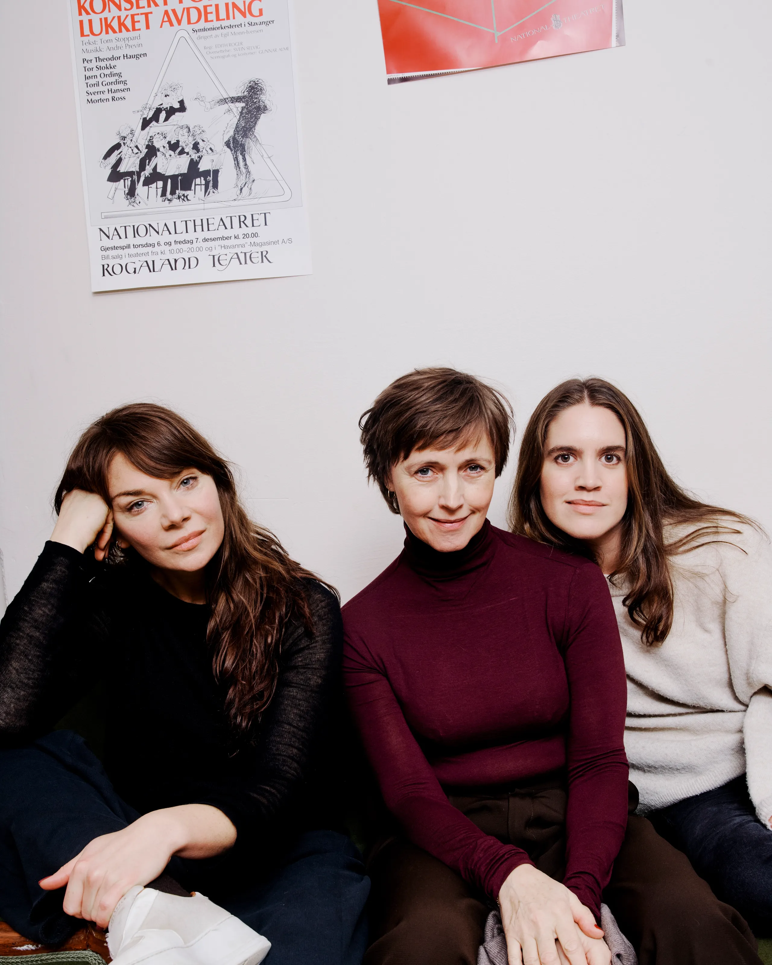 Tre kvinner sitter i en grønn sofa mot en hvit vegg.