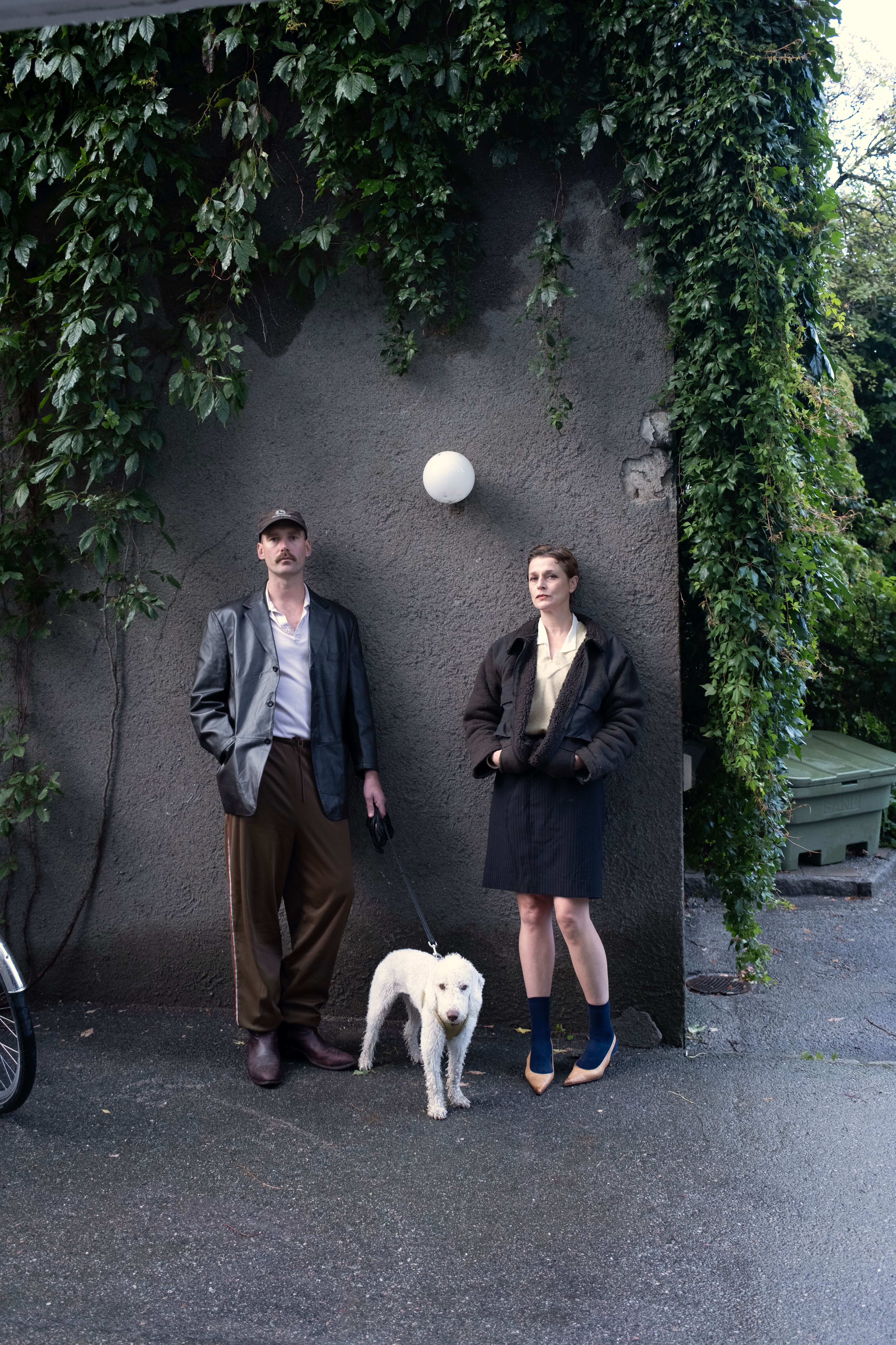 To mennesker og en hund ser mot kameraet