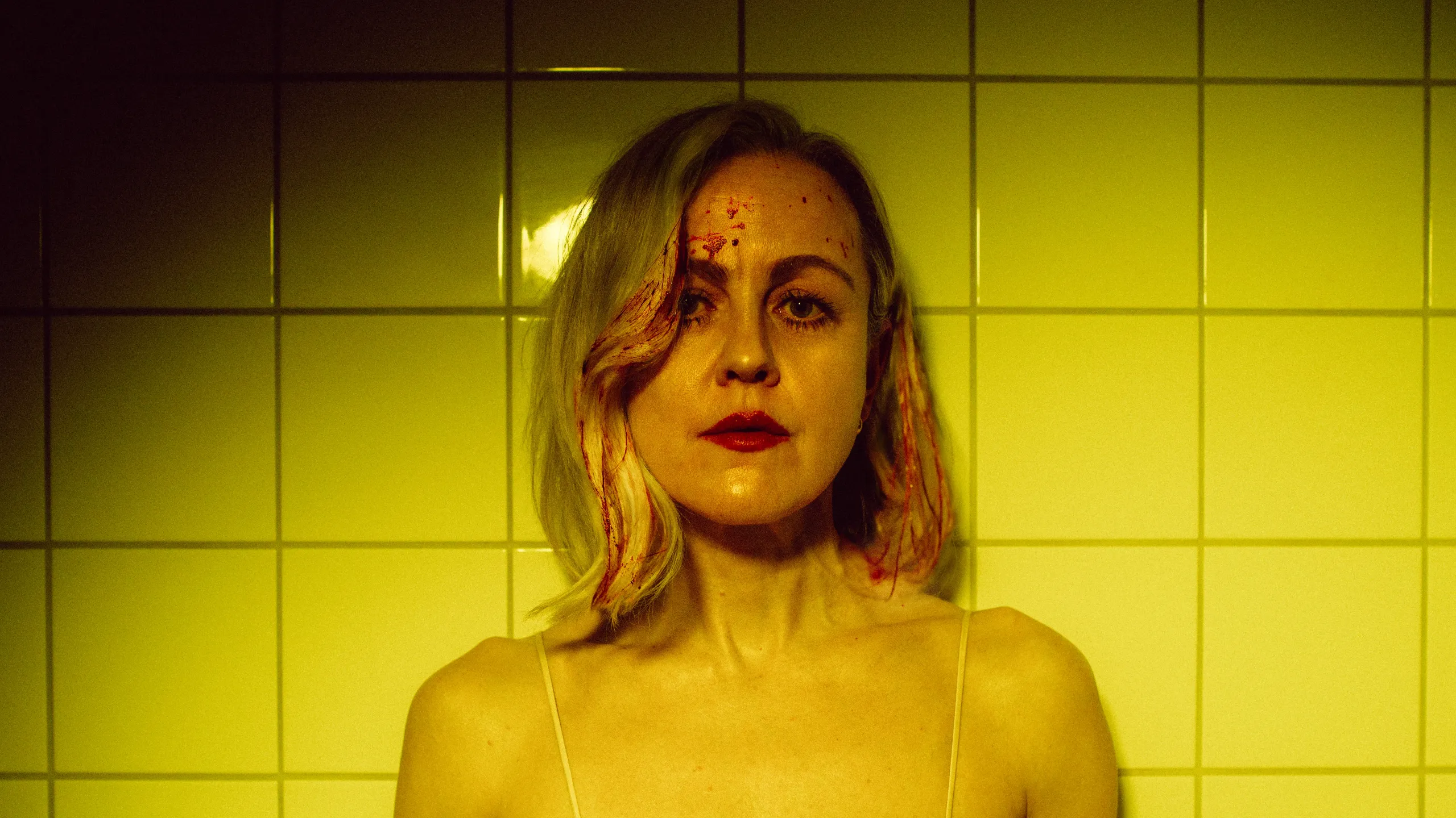 Portrett av kvinne med blod i fjeset mot gule fliser