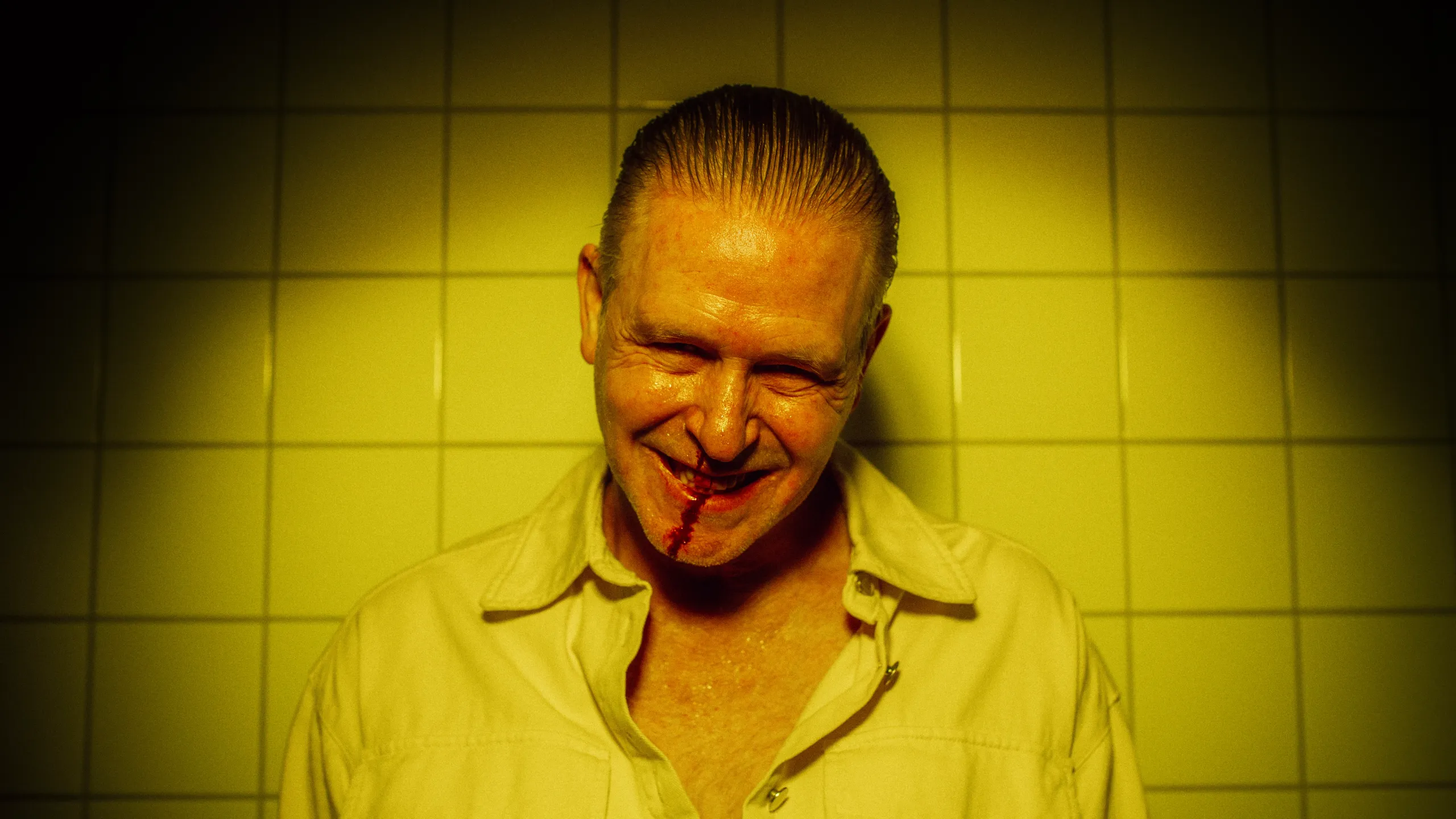 Portrett av mann med blod i fjeset mot gule fliser