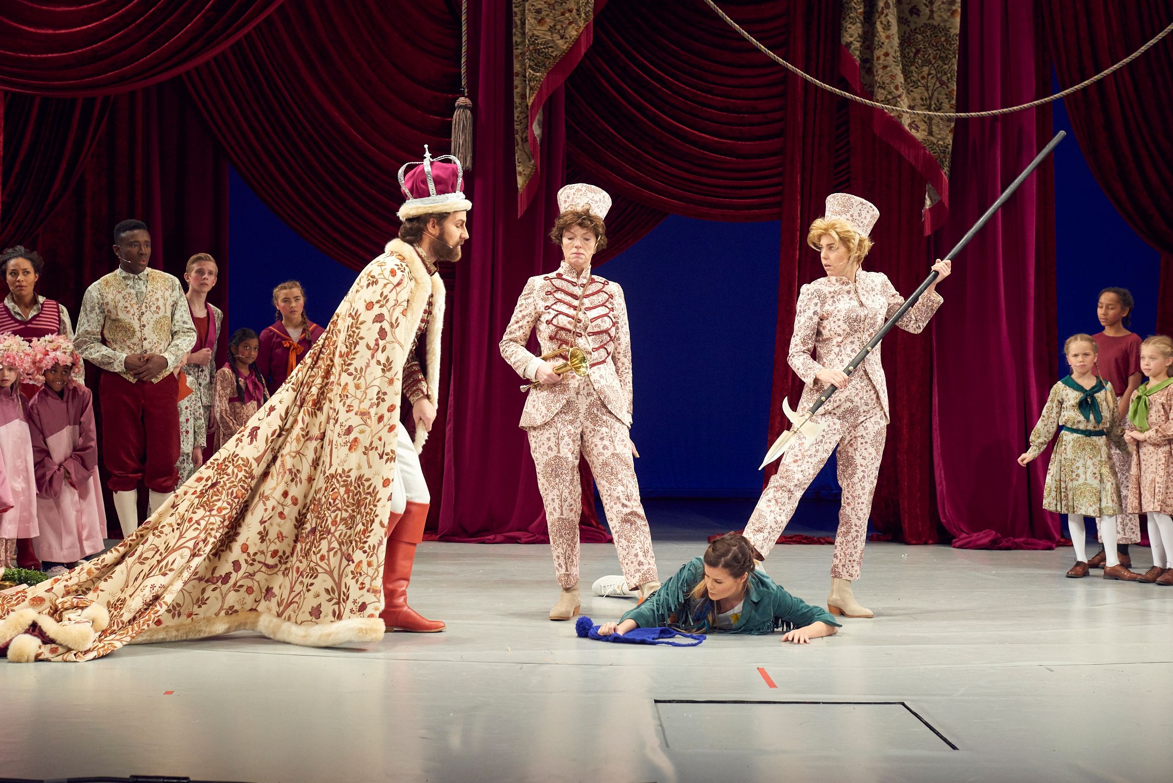 Soldater holder en jente nede, mens en konge ser på henne.