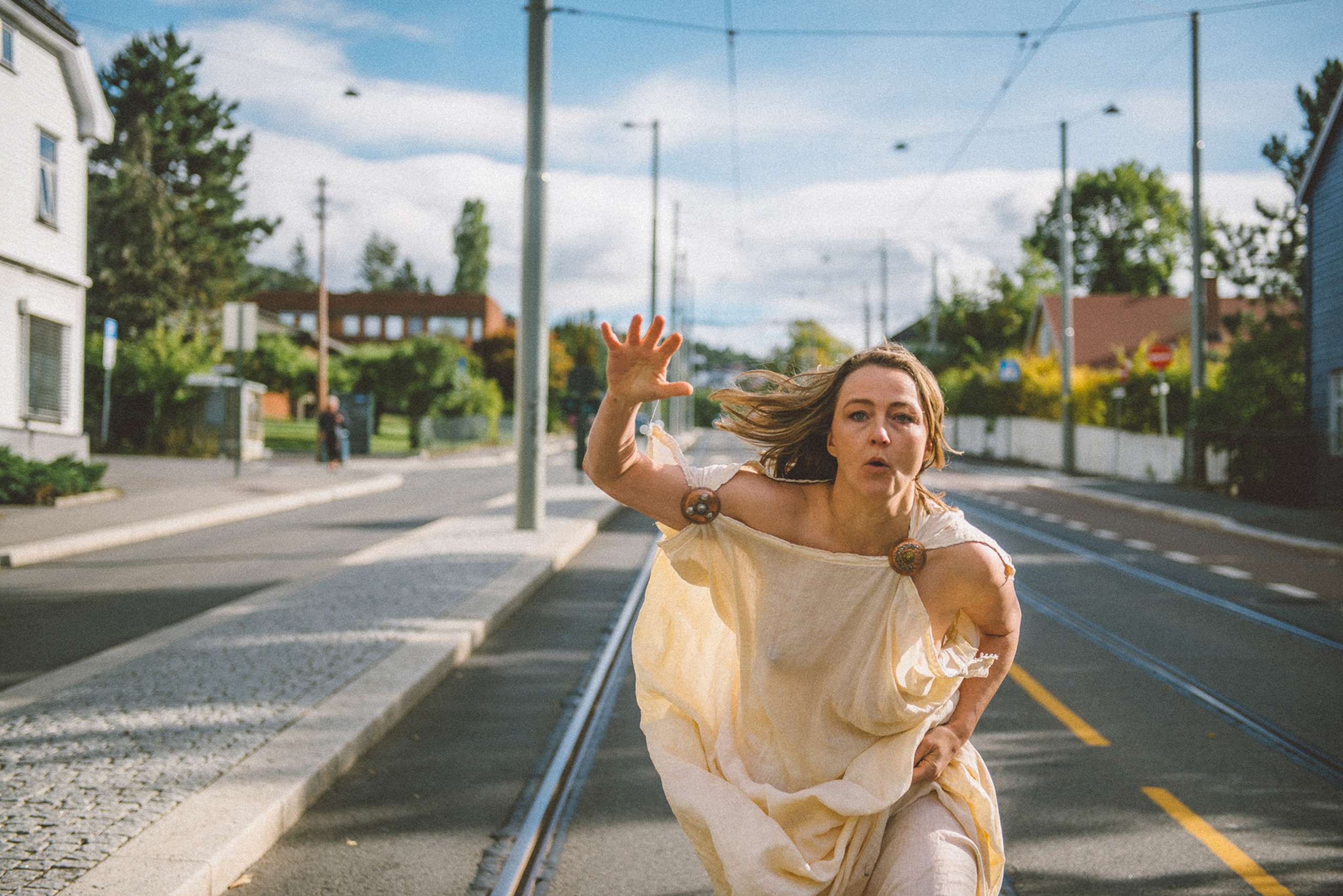 Kvinne i toga løper nedover gata