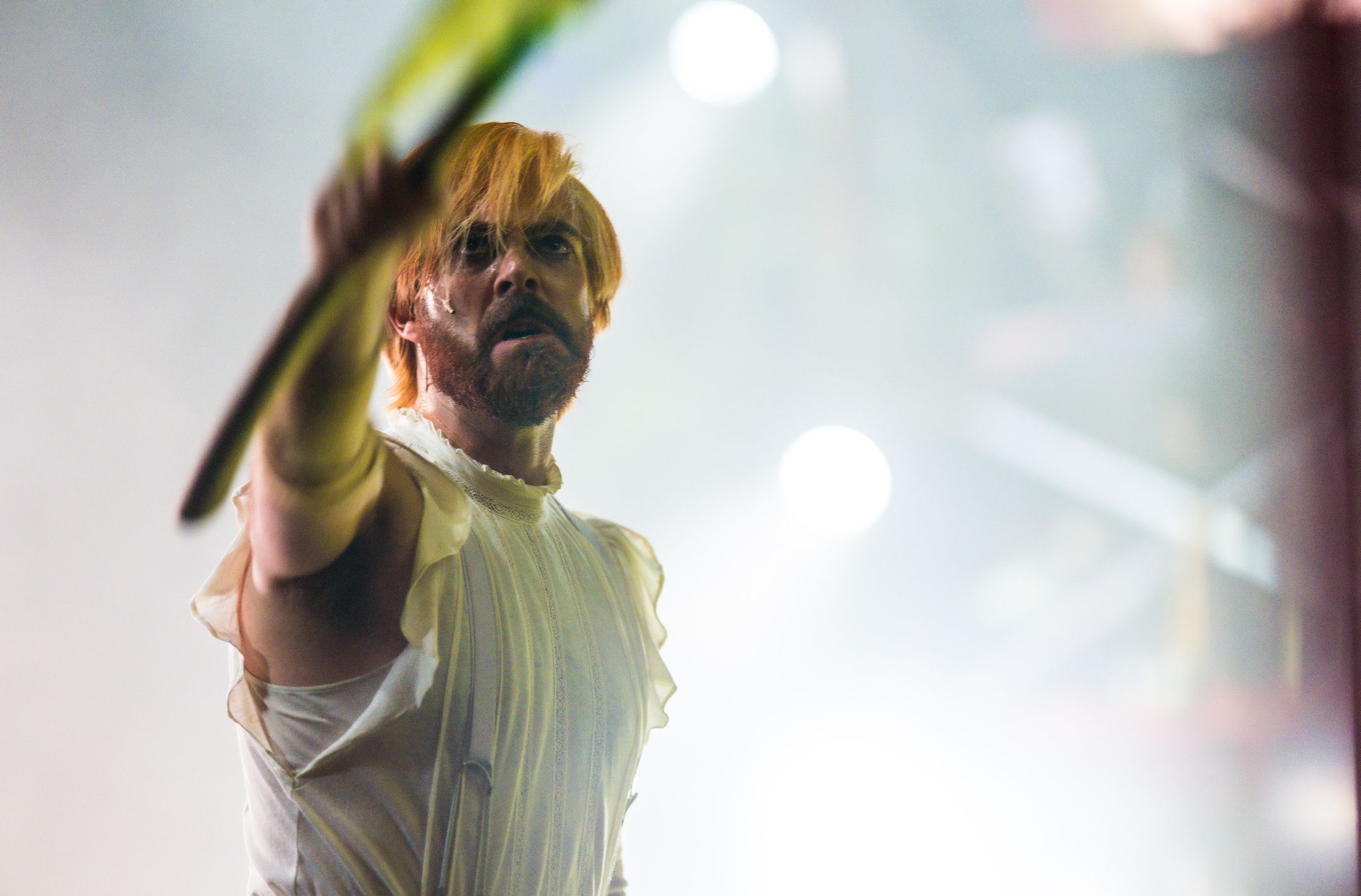 Mann i hvitt kostyme og hvitt lys holder alvorlig frem en arm