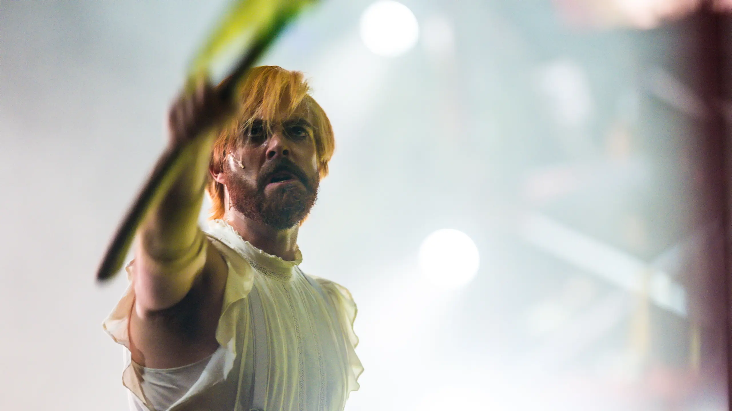 Mann i hvitt kostyme og hvitt lys holder alvorlig frem en arm