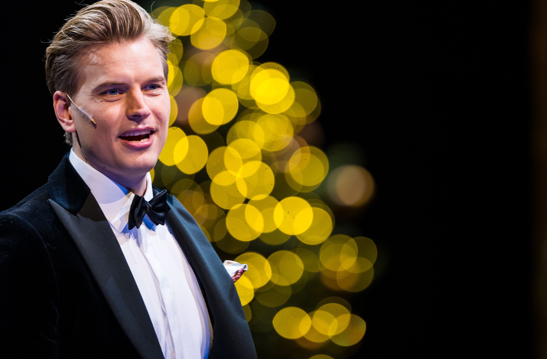 Mann med i smoking foran julelys