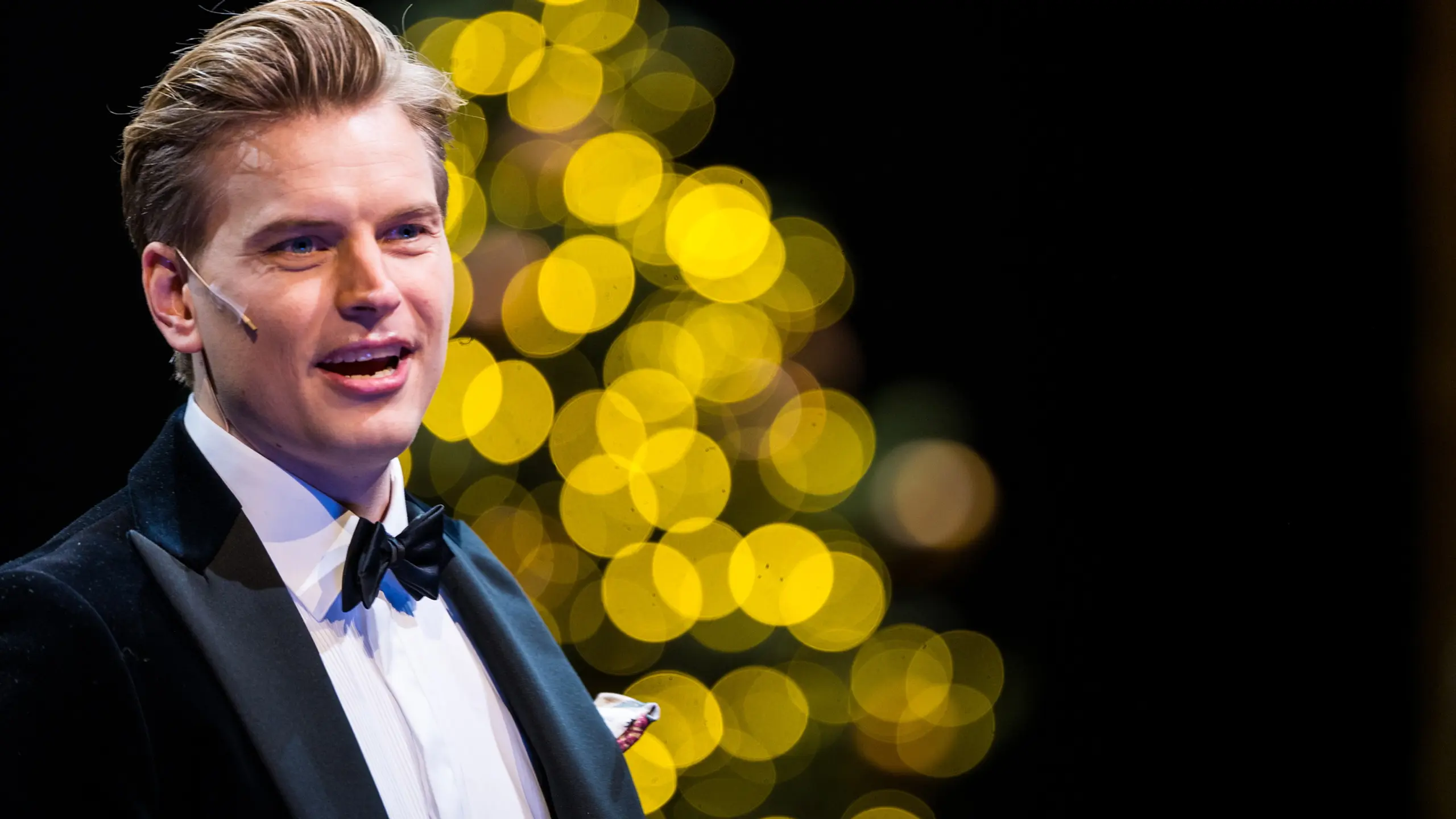 Mann med i smoking foran julelys