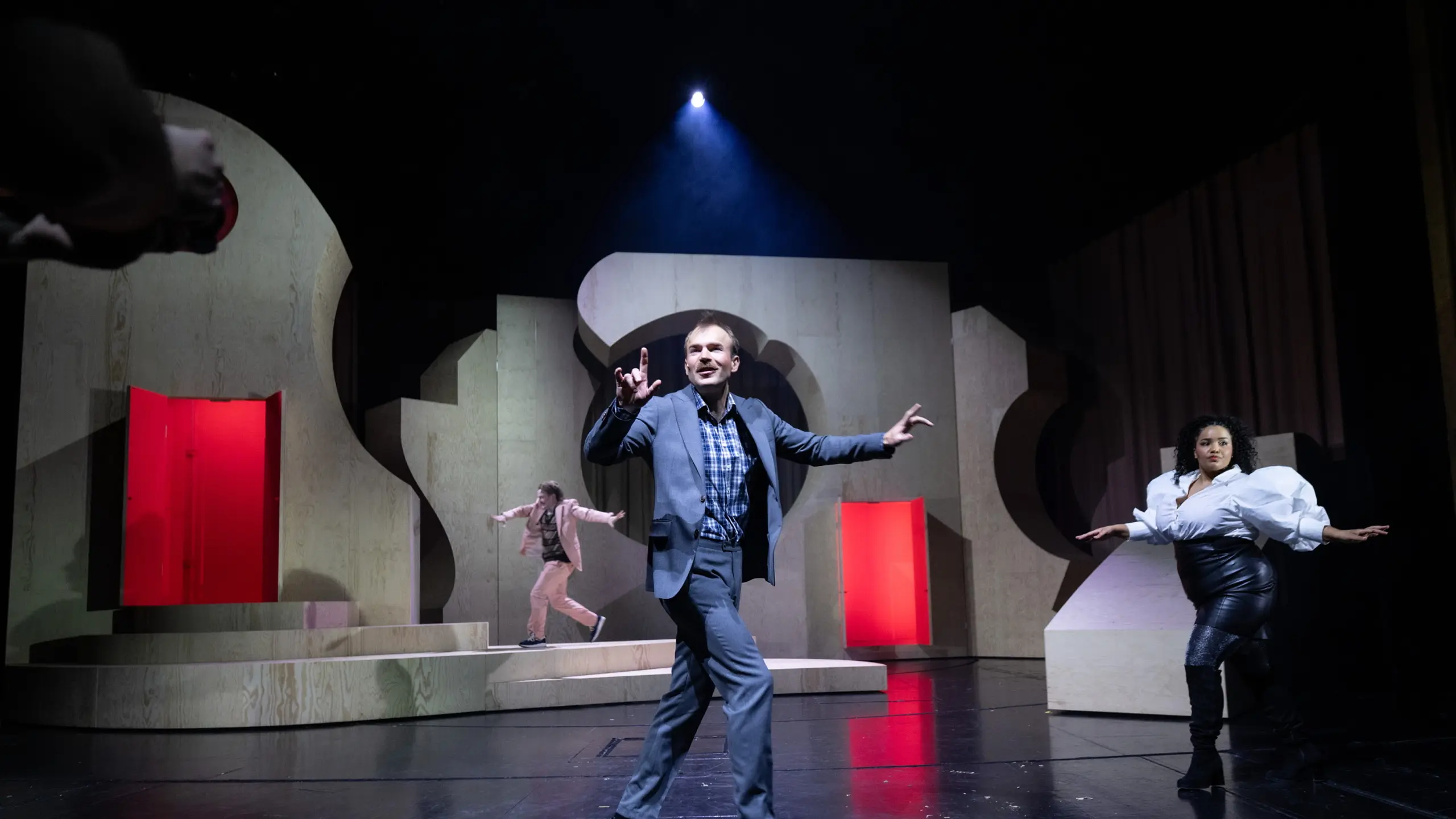 Skuespillere som løper rundt på en scene med trescenografi i organiske former