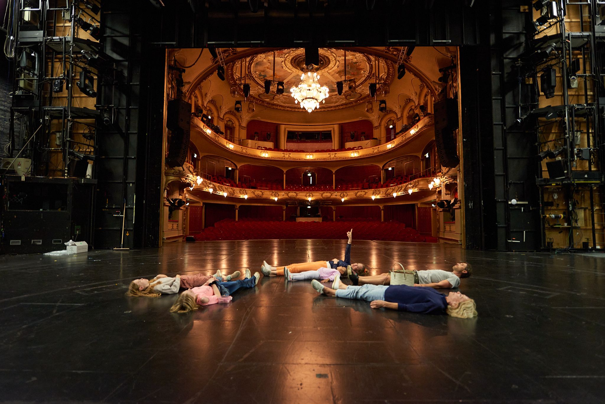 Voksne og barn ligger på ryggen på Hovedscenen og ser opp i taket
