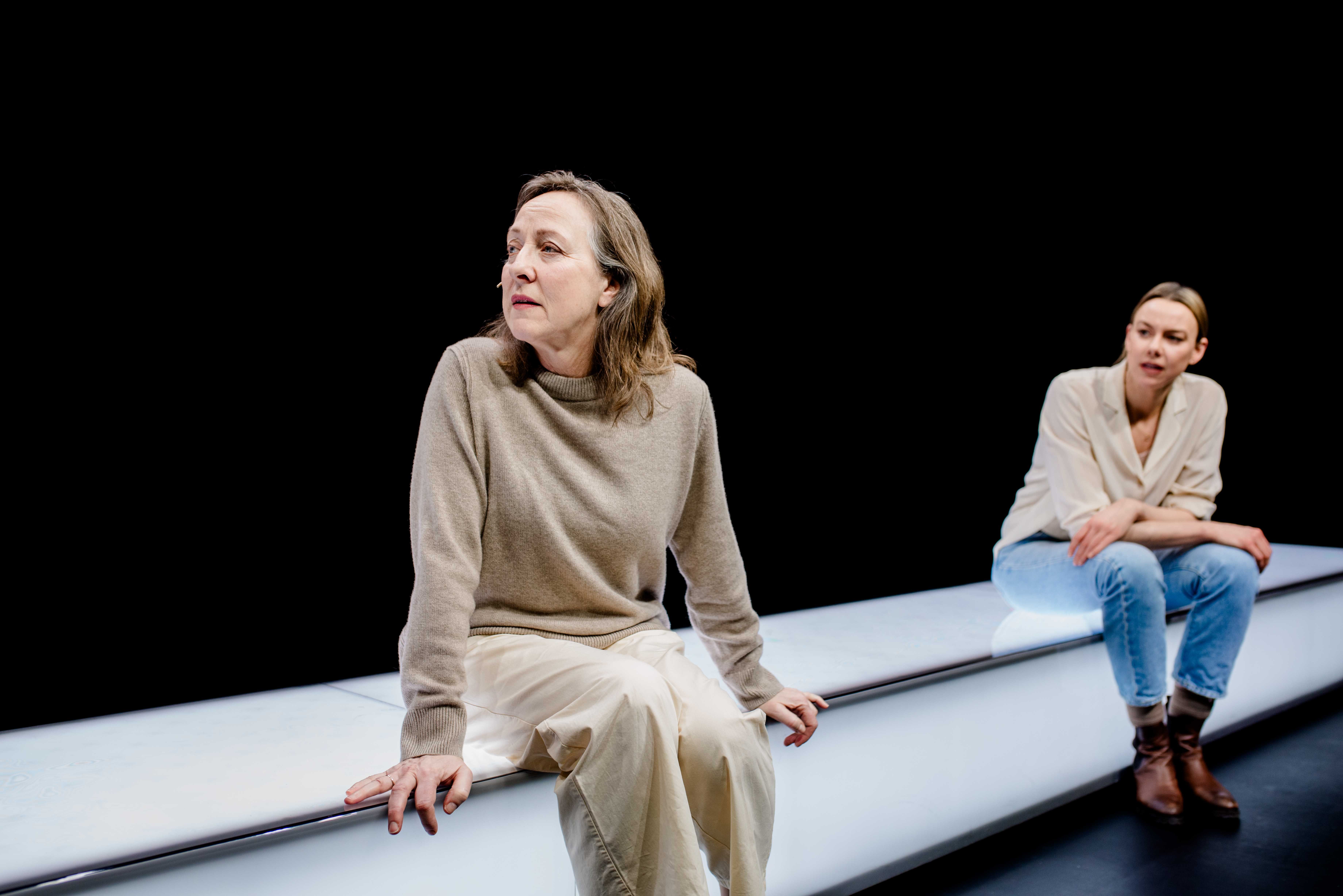 To kvinner sitter på en lang hvit benk