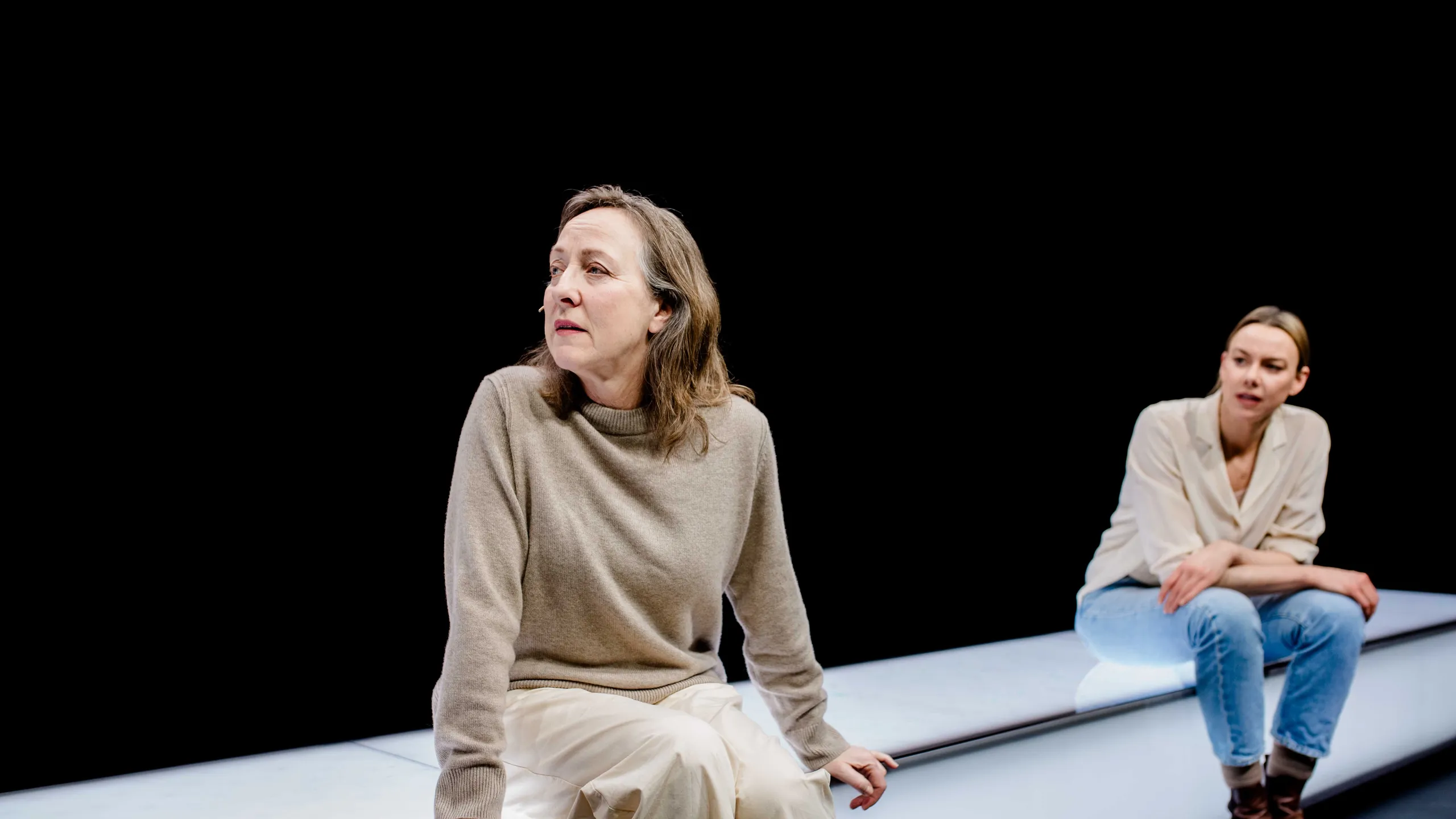 To kvinner sitter på en lang hvit benk