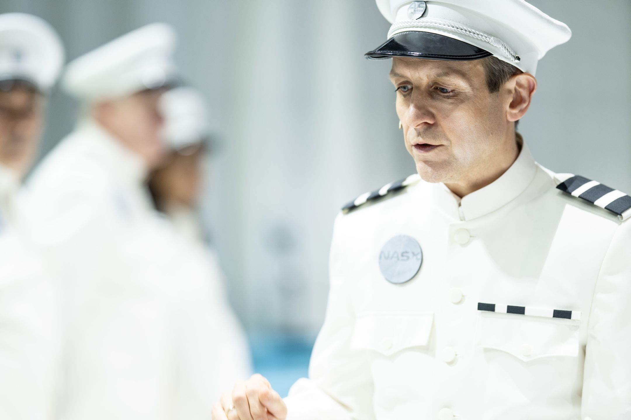 Person i hvit uniform og kaps med merke “NASY”, snakker mens andre uniformerte personer er uklare i bakgrunnen