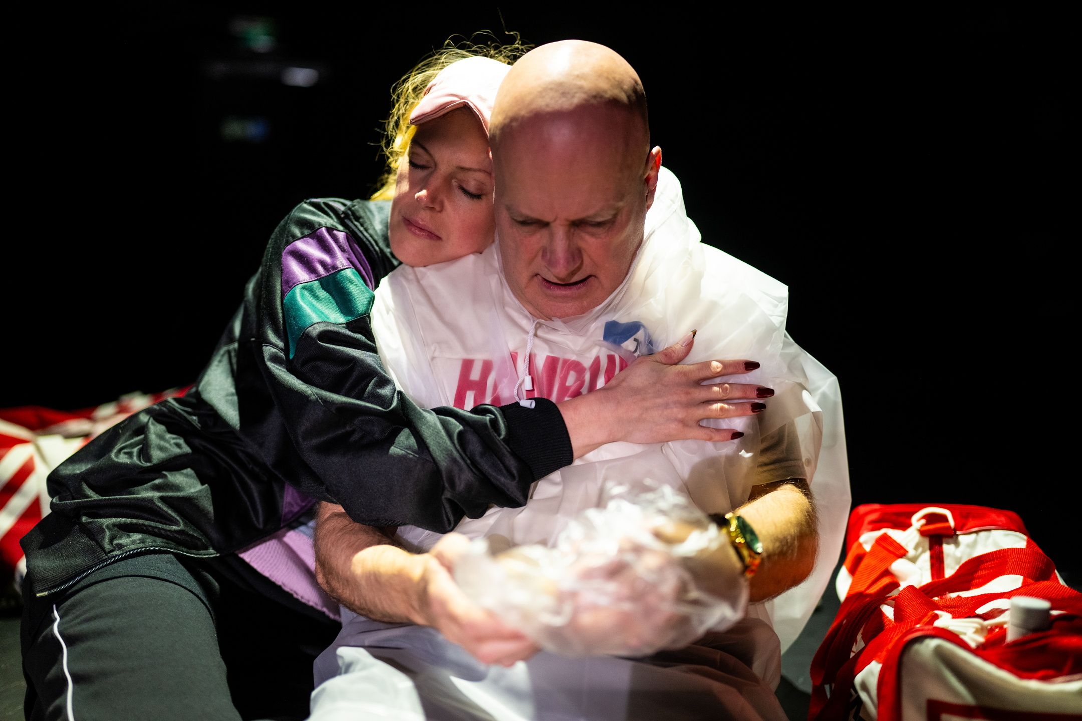 Kvinne klemmer mann iført plastponcho med påskriften "Hamburg", begge med lukkede øyne