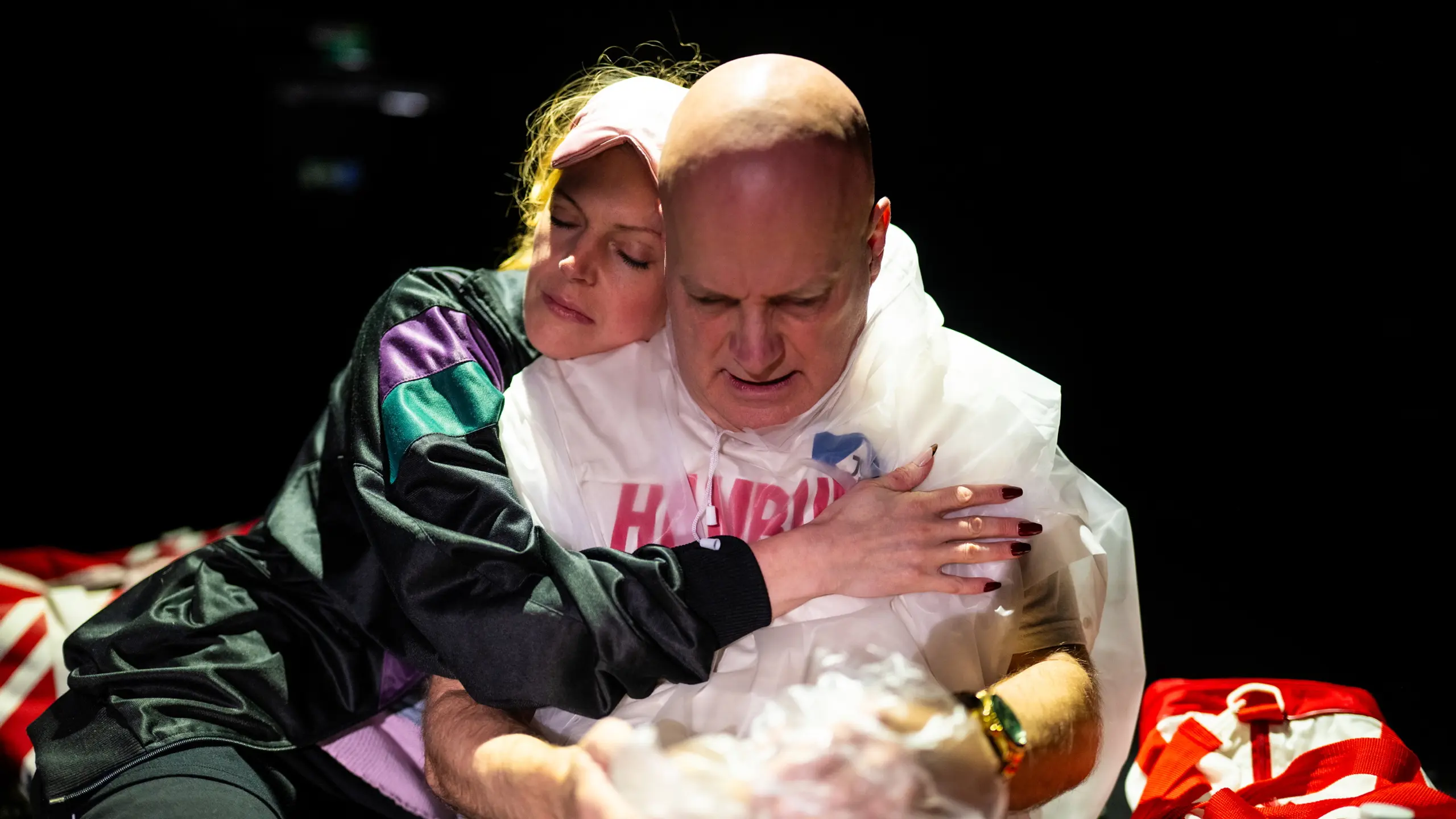 Kvinne klemmer mann iført plastponcho med påskriften "Hamburg", begge med lukkede øyne