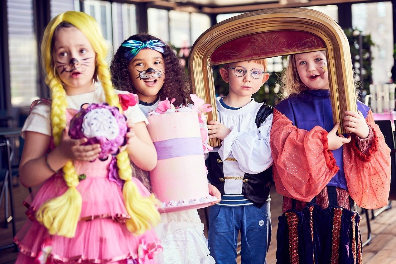 Fire barn i kostymer med kake og en liten prosceniumsbue