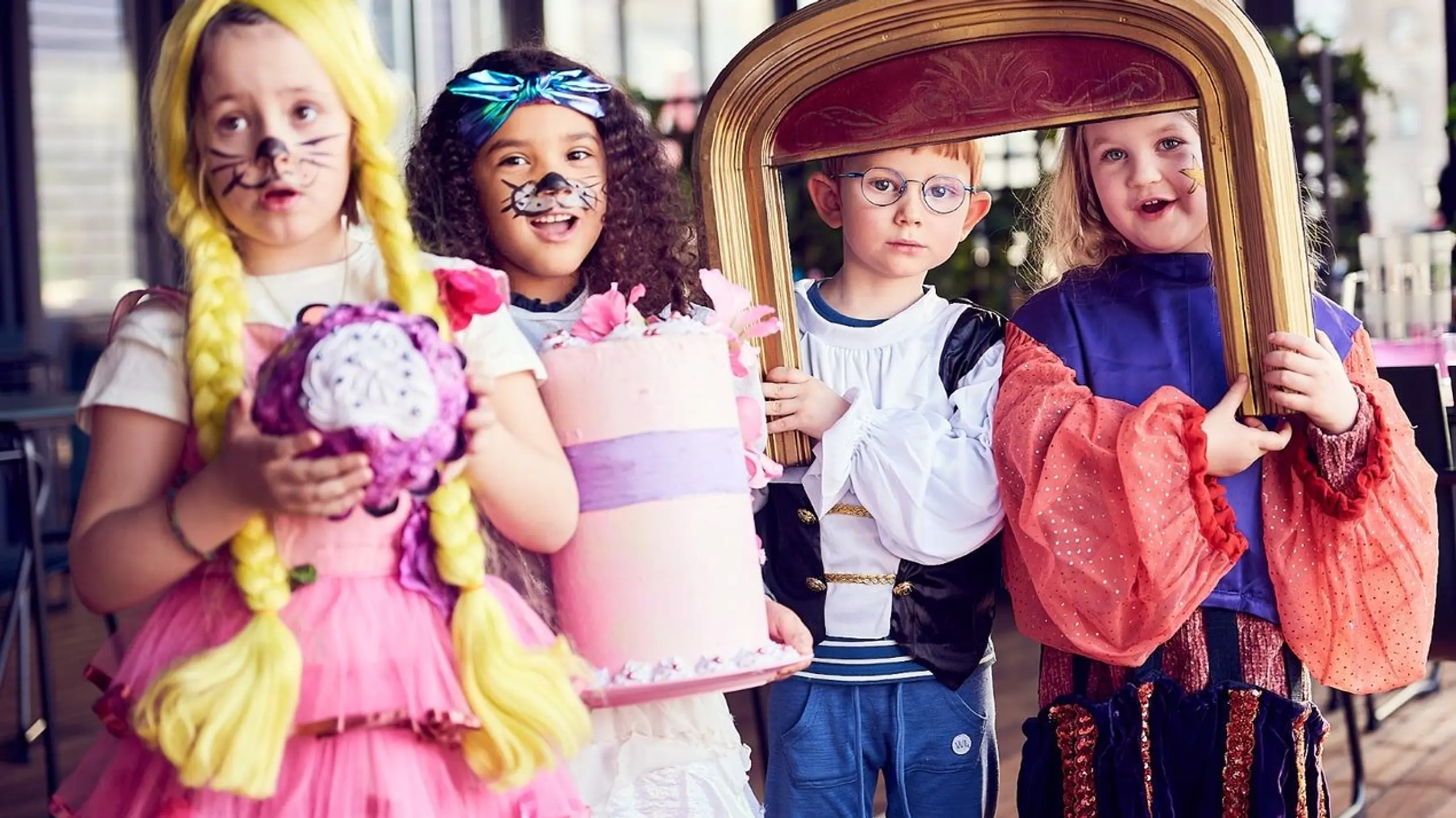 Fire barn i kostymer med kake og en liten prosceniumsbue