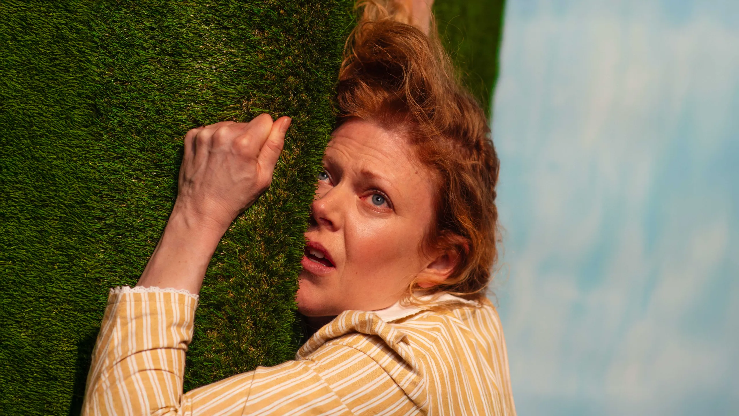 Kvinne som klamrer seg til kunstgress i tiltet bilde