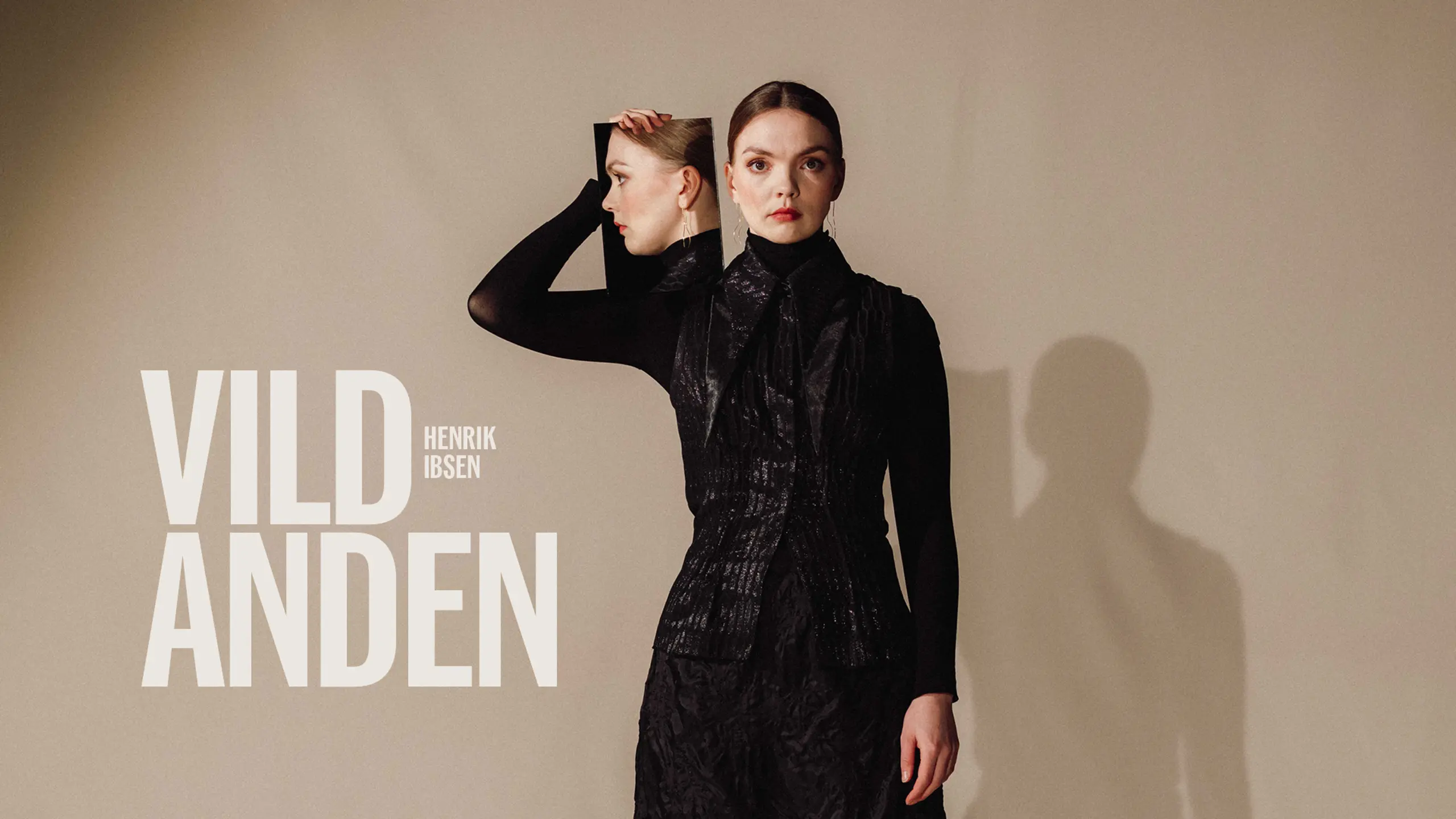 Kvinne i svart holder opp et speil ved siden av fjeset, så vi ser profilen hennes i det med tekst "Vildanden Henrik Ibsen"