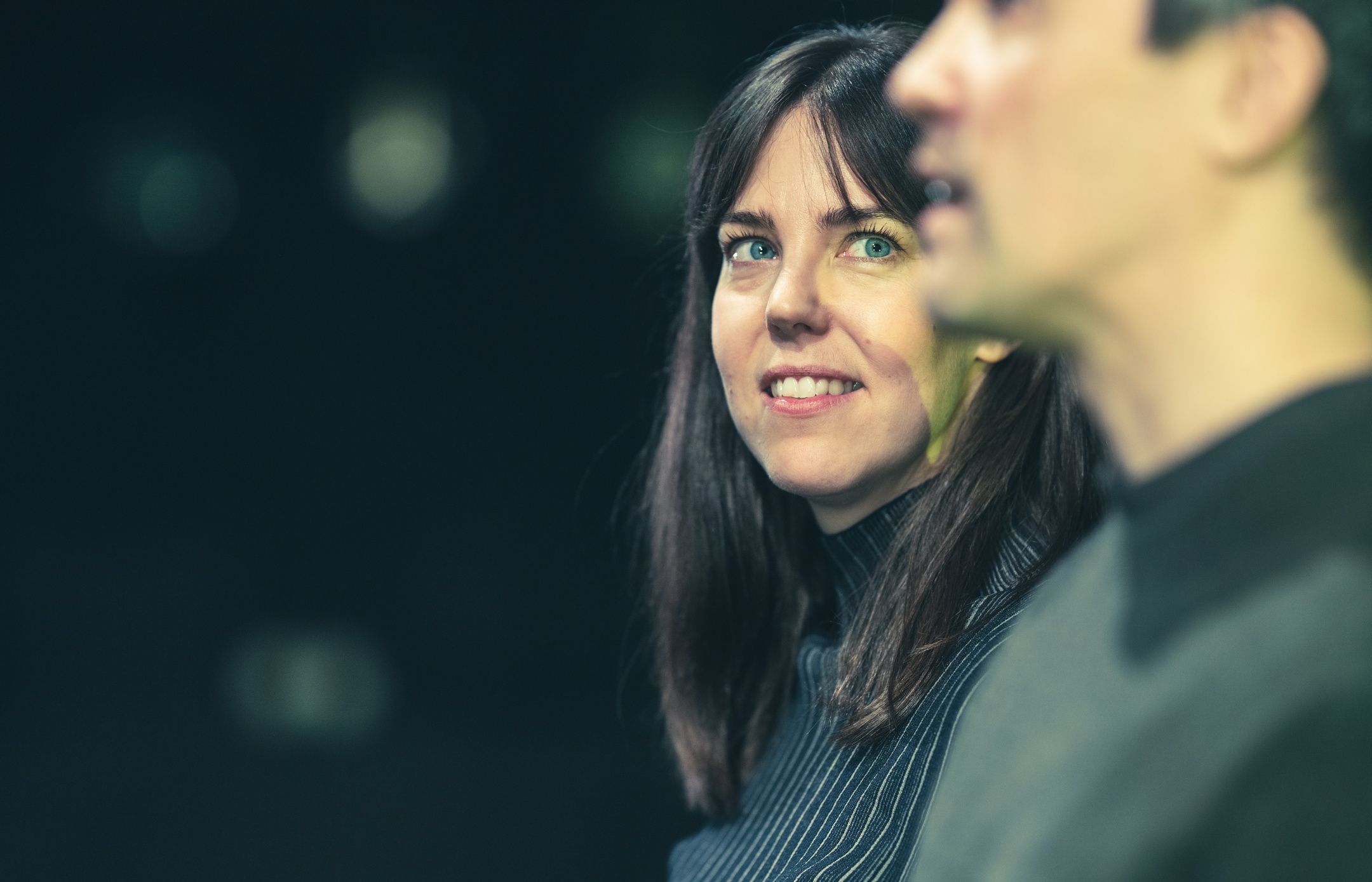 Kvinne smiler mens hun ser på en mann som ser rett fram