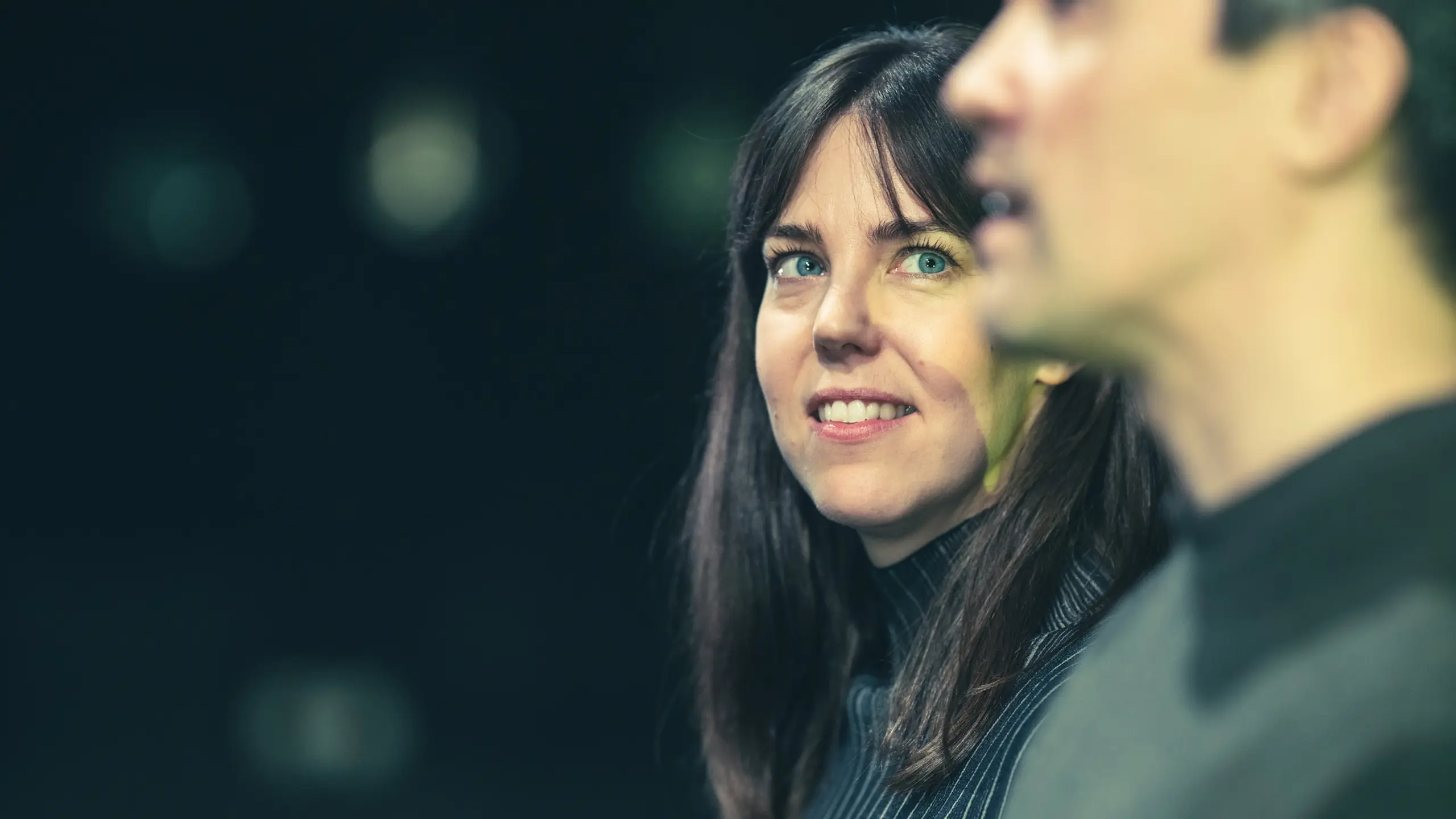 Kvinne smiler mens hun ser på en mann som ser rett fram