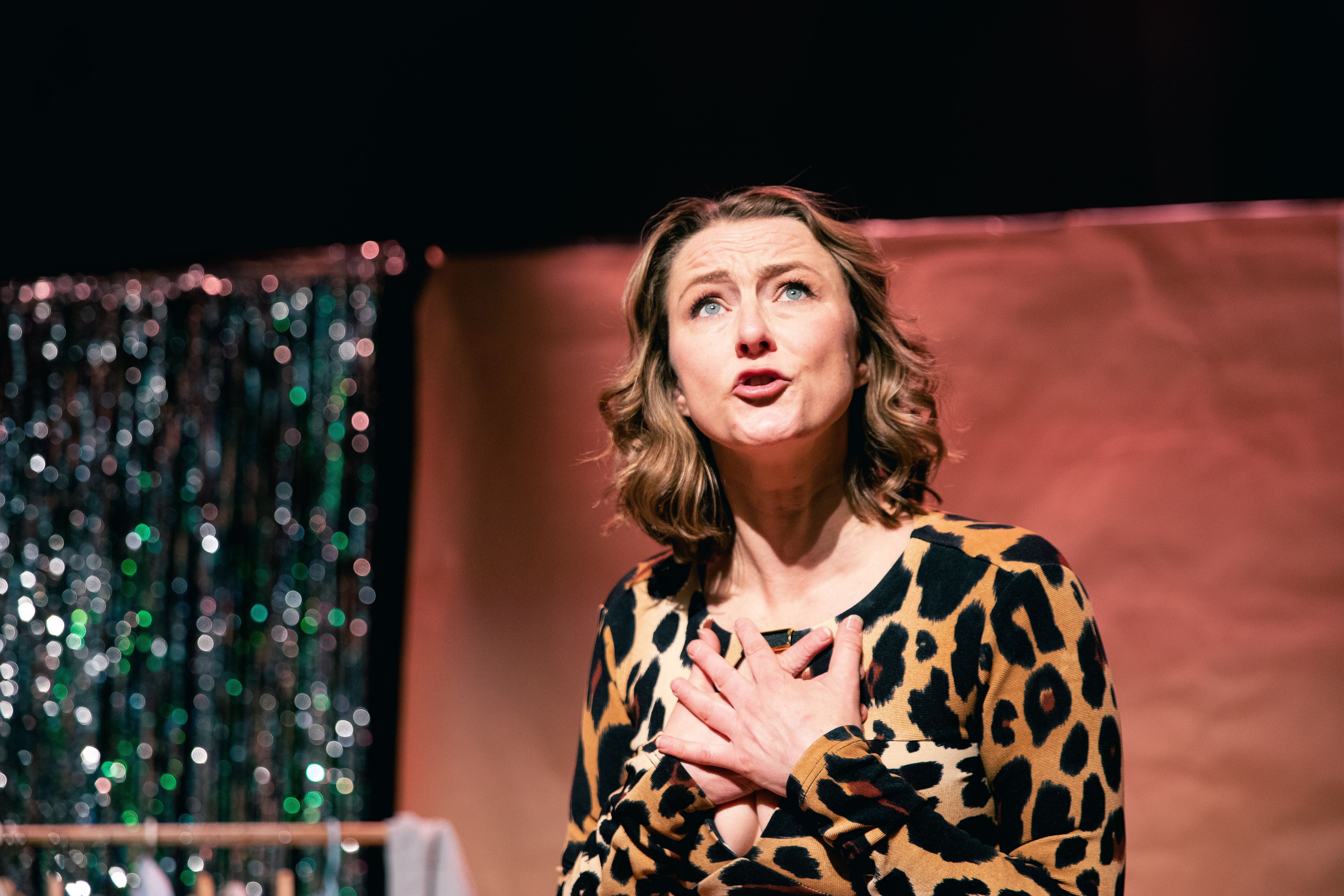 Kvinne i leopardmønstret topp prater engasjert med hendene mot brystet