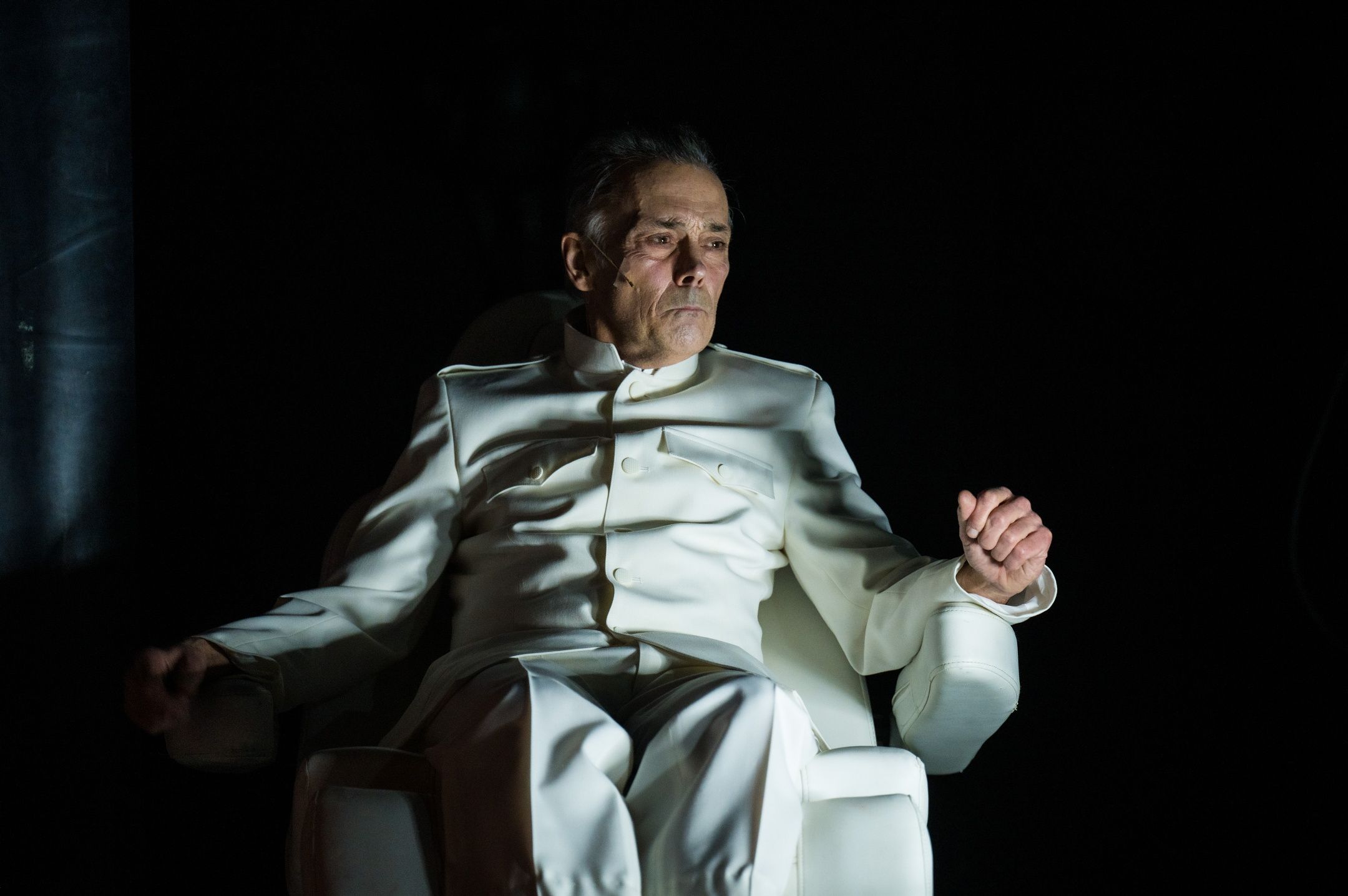 Mann i lys uniform som sitter i en stol