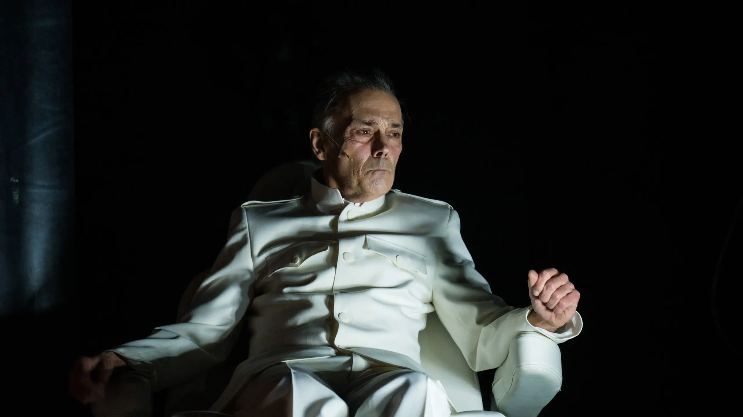 Mann i lys uniform som sitter i en stol