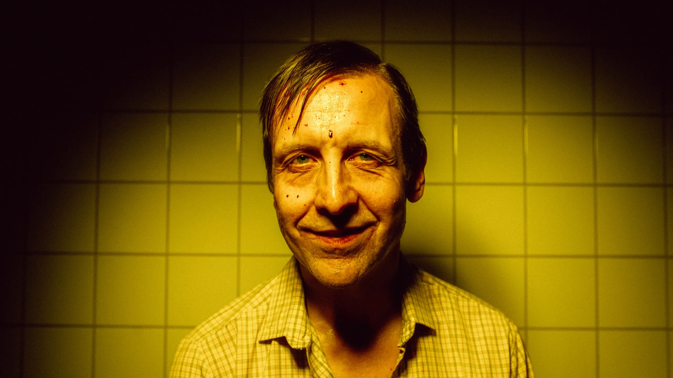 Portrett av mann med blod i fjeset mot gule fliser