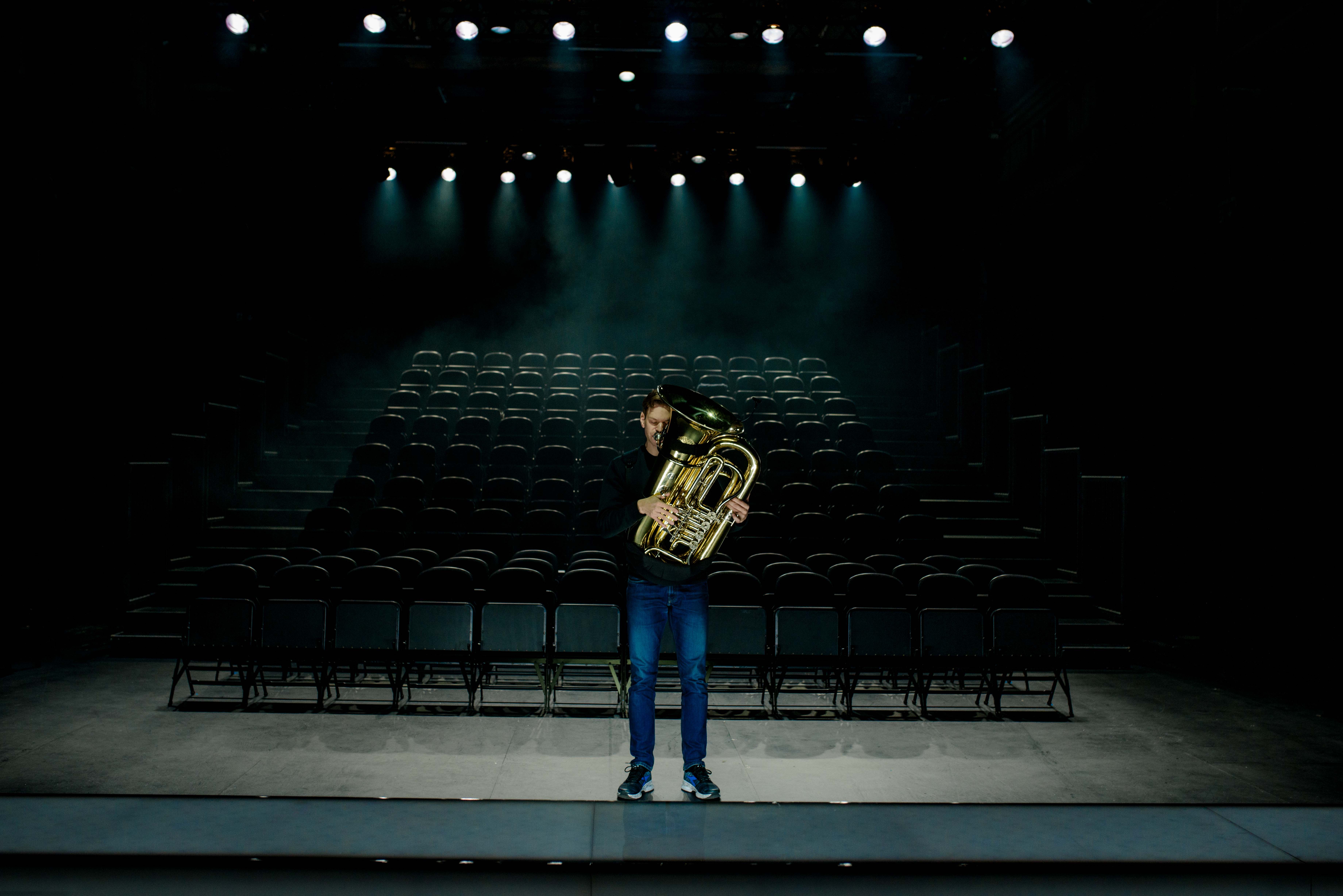 Musiker Kristoffer Kompen står foran et mørkt og tomt amfi med en tuba