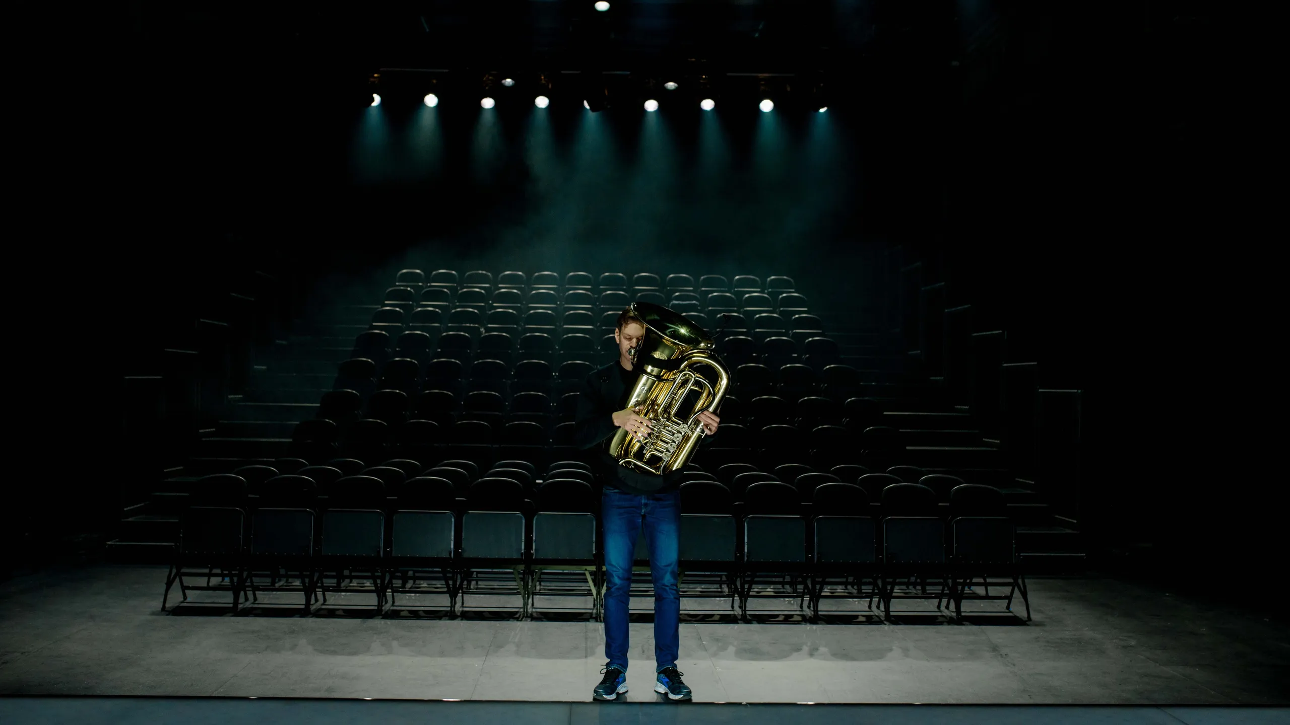 Musiker Kristoffer Kompen står foran et mørkt og tomt amfi med en tuba