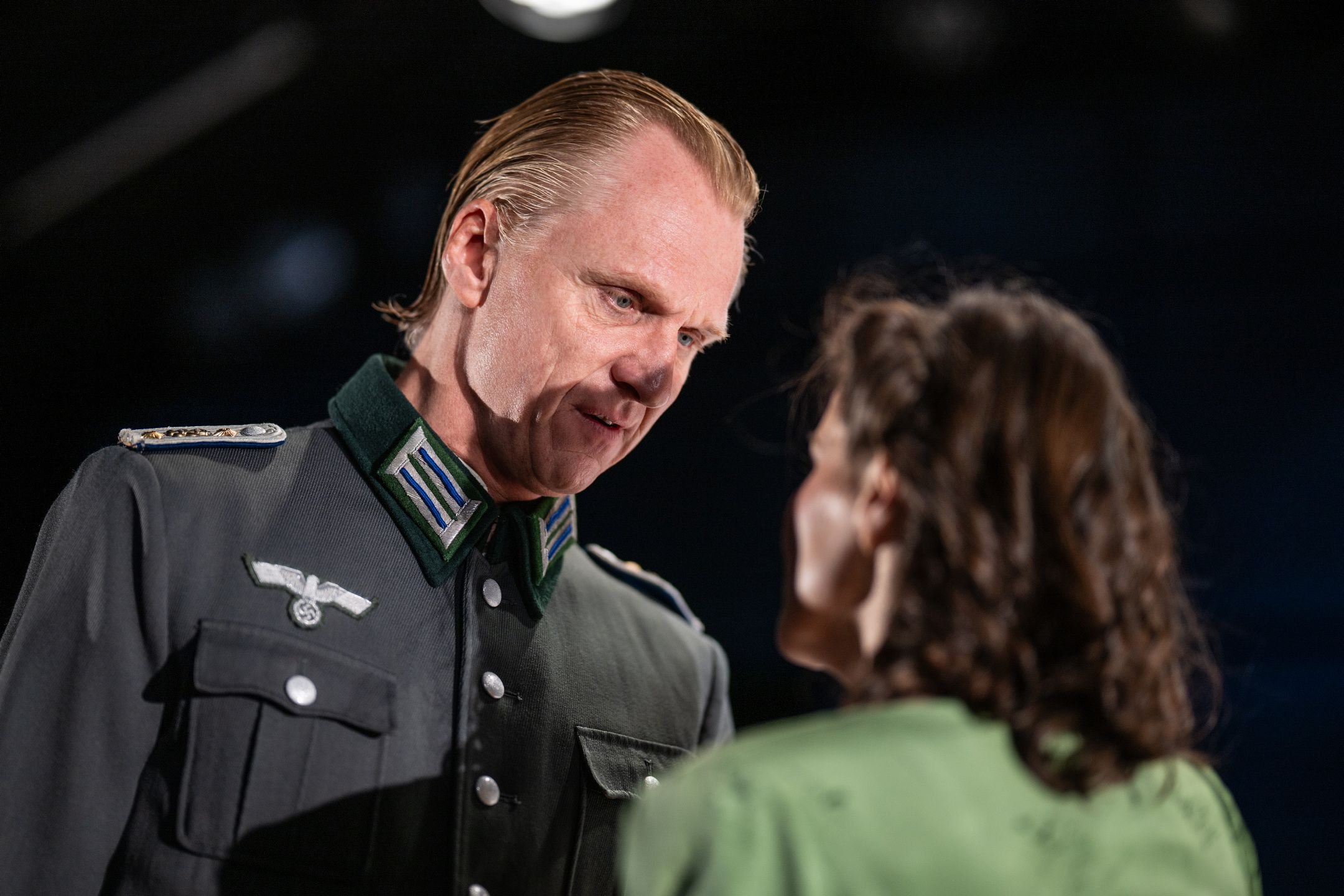 Mann i SS-uniform ser på kvinne i grønn kjole