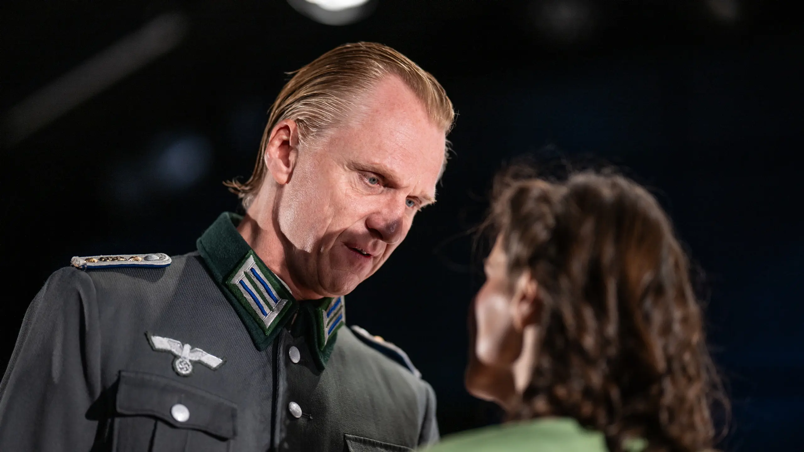 Mann i SS-uniform ser på kvinne i grønn kjole