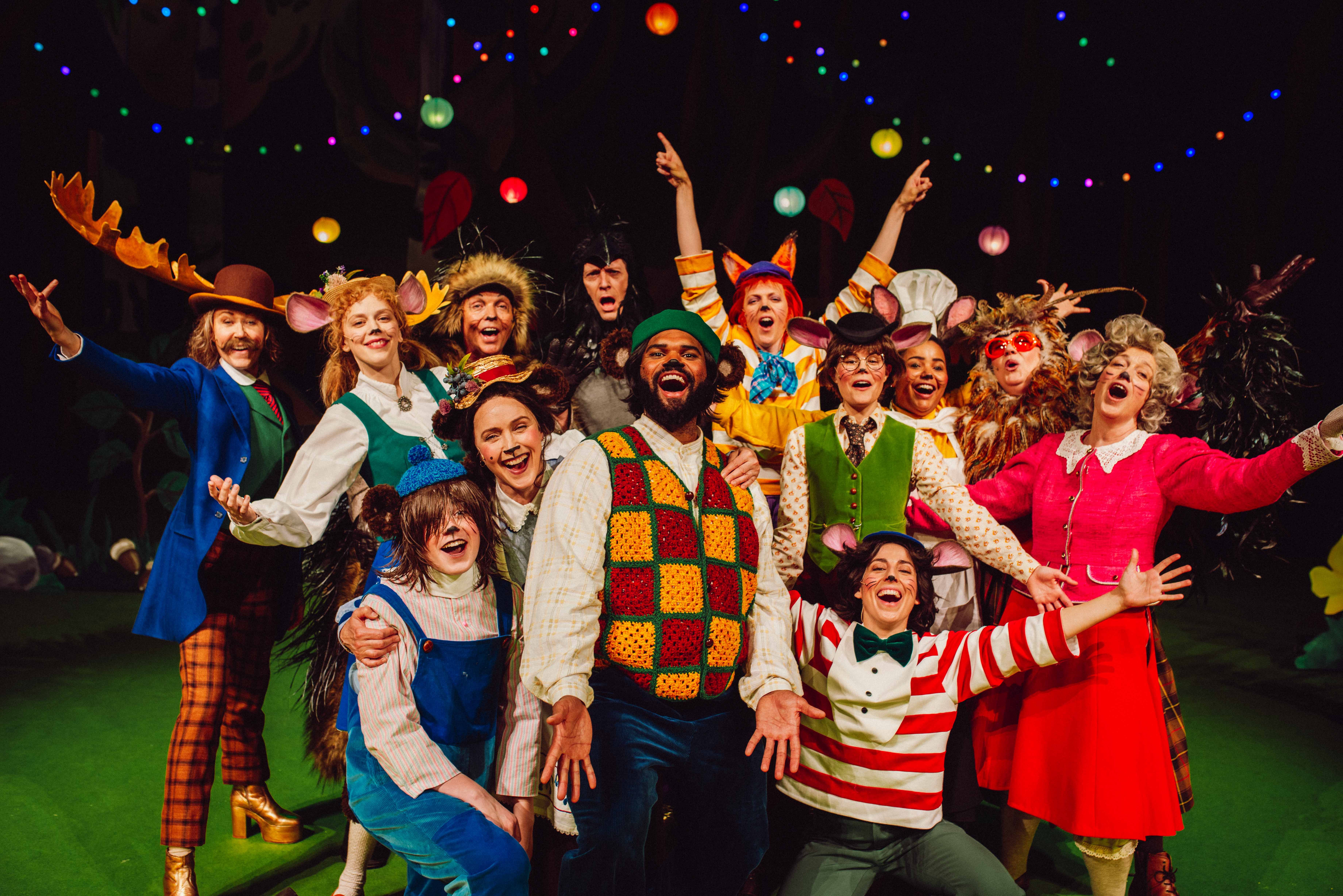 Hele ensemblet i dyrekostymer jubler samlet foran dekor og fargerike lyslenker.