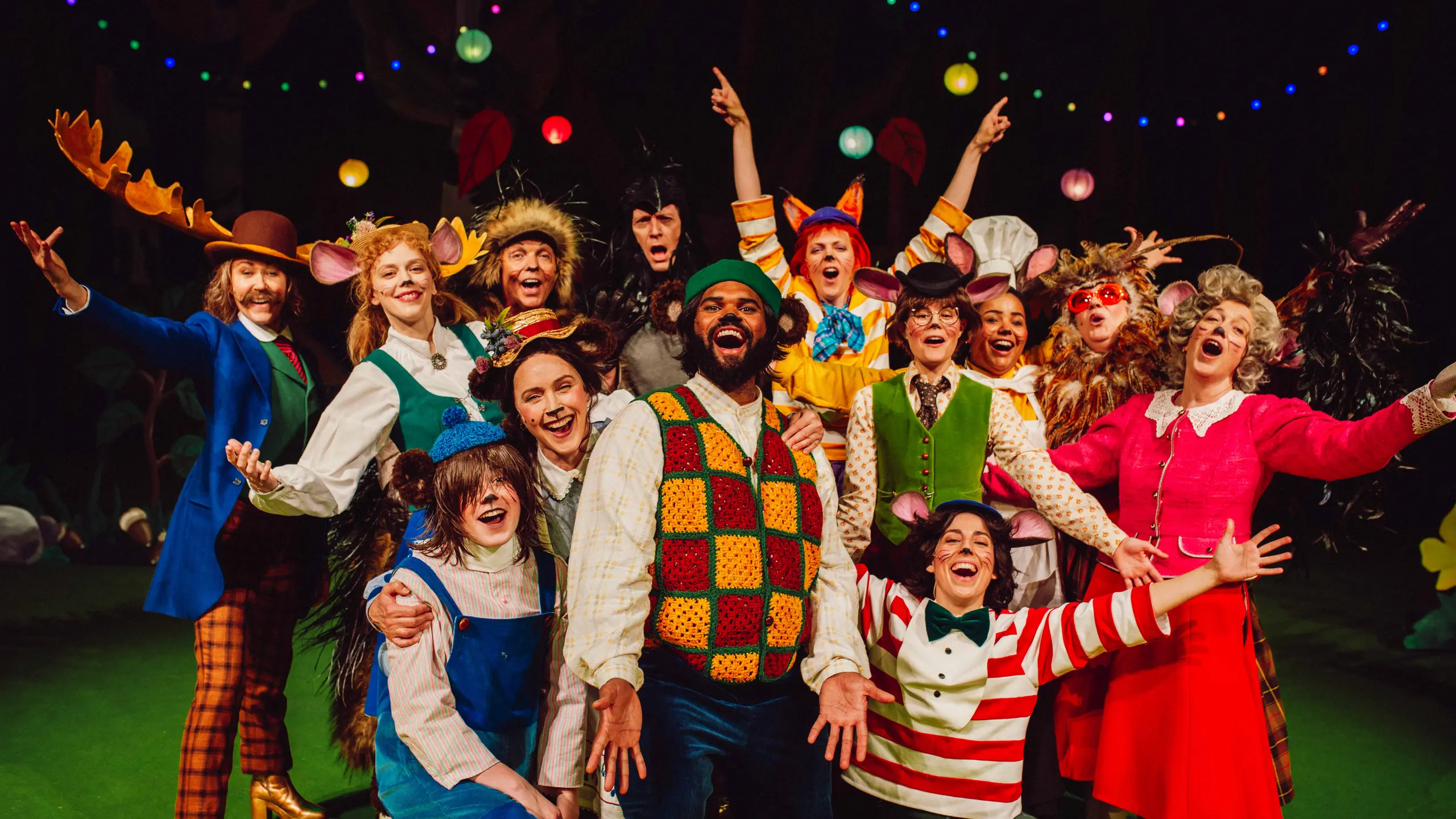Hele ensemblet i dyrekostymer jubler samlet foran dekor og fargerike lyslenker.