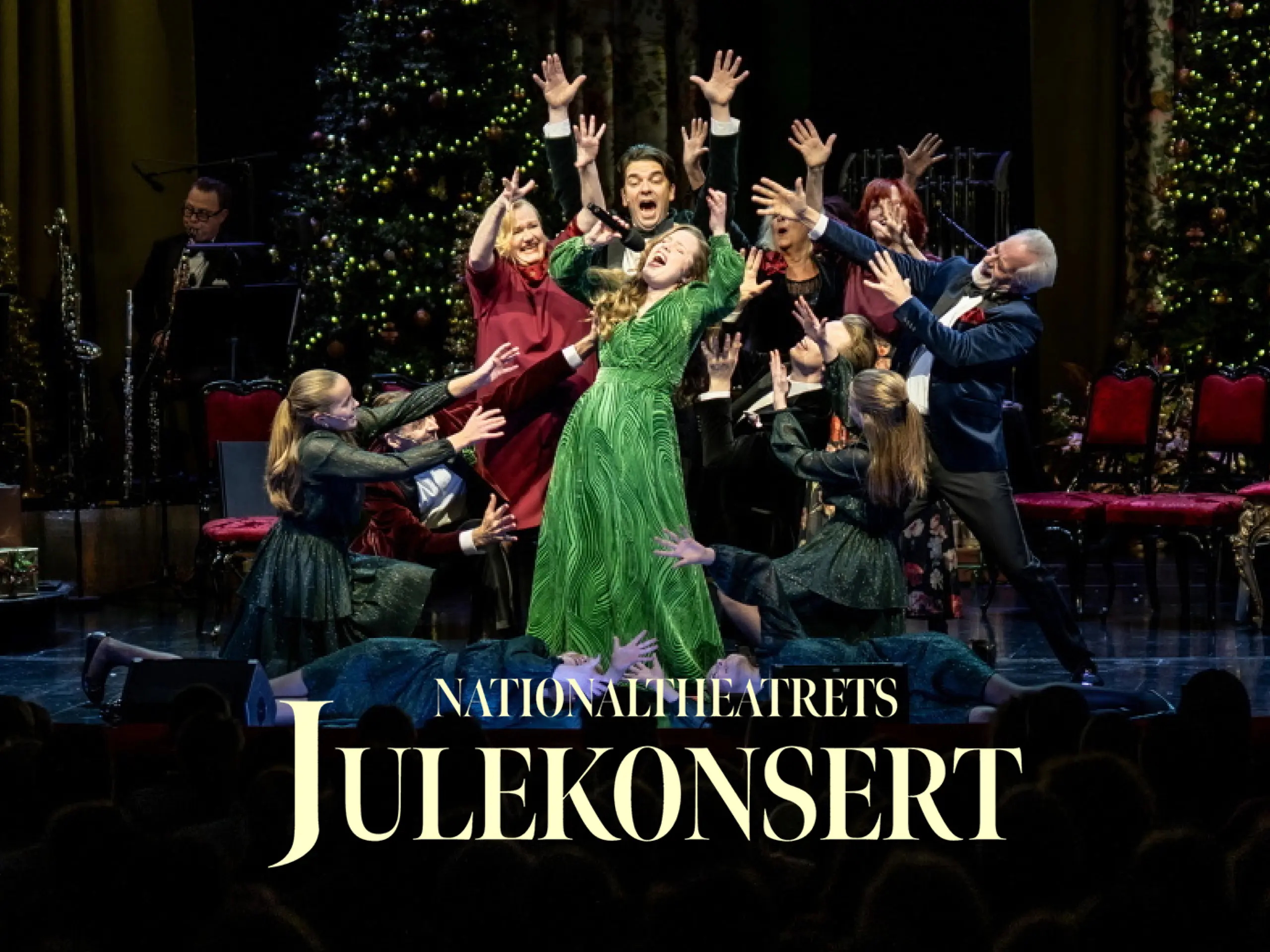 En gruppe som står og synger på scenen med tekst "Nationaltheatrets julekonsert"
