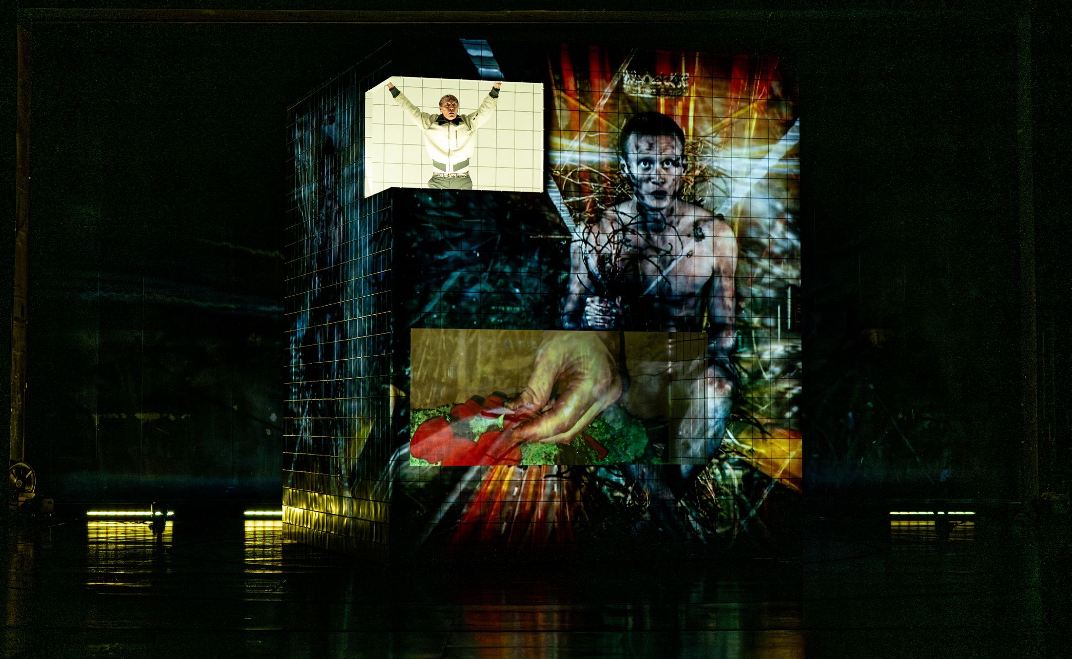 Person strekker armene ut øverst på en projisert kube med surrealistisk bilde av mann med krone og tornekrans.