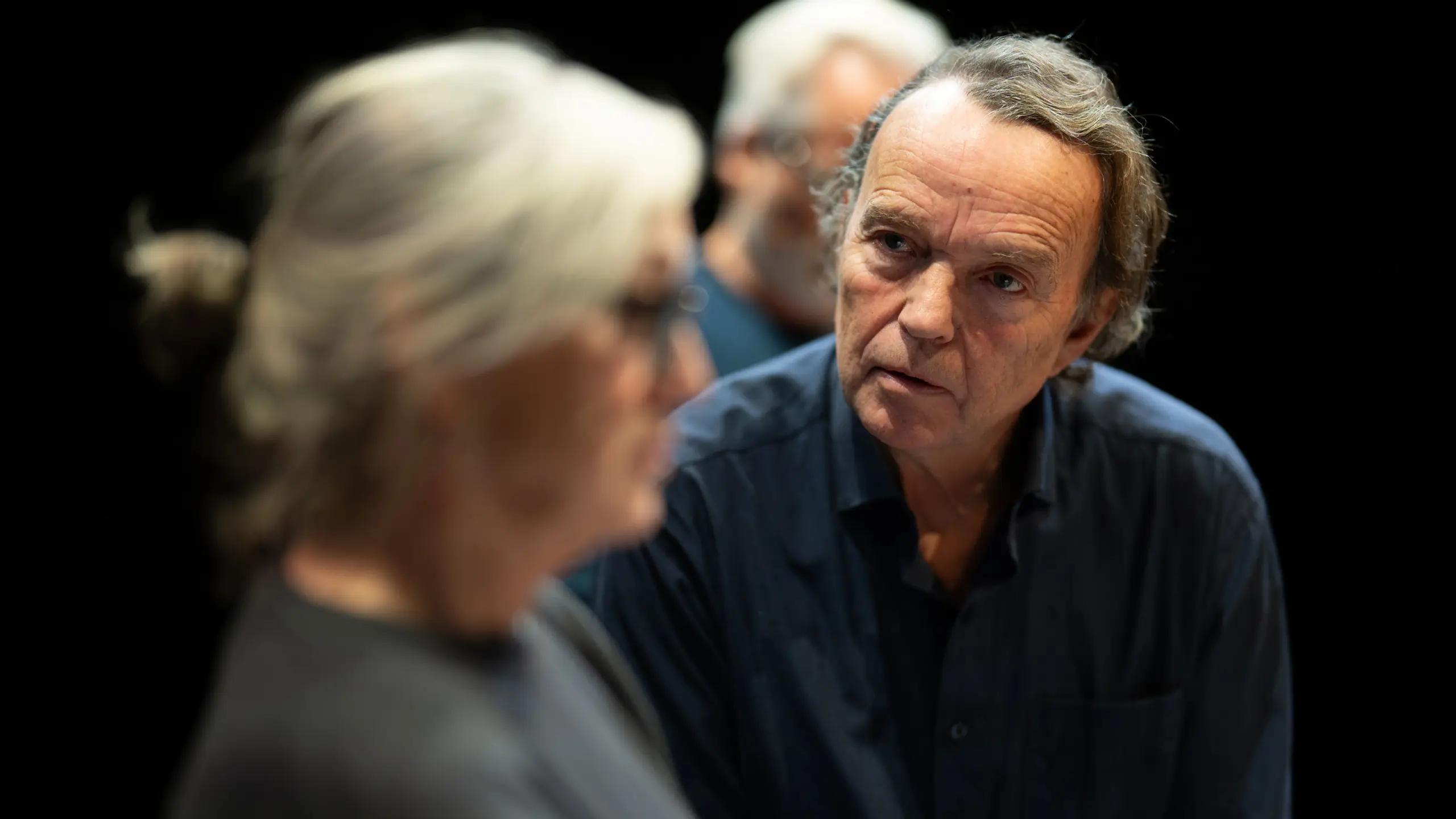 Mann sitter og ser på en kvinne, som kikker rett fram