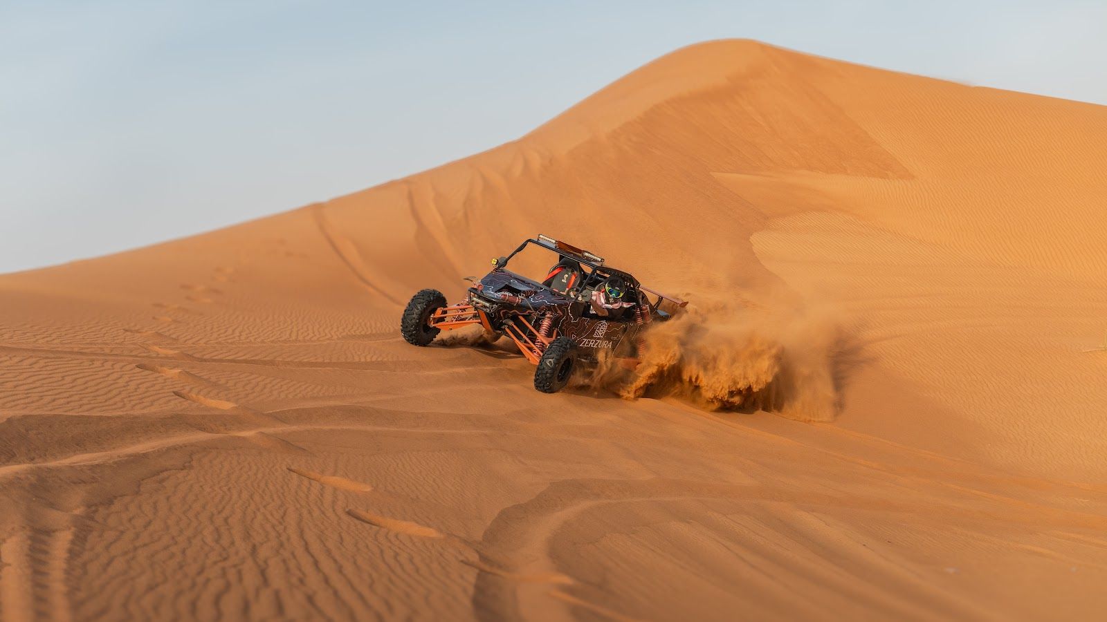 A Zerzura dune buggy carving through a steep sand dune