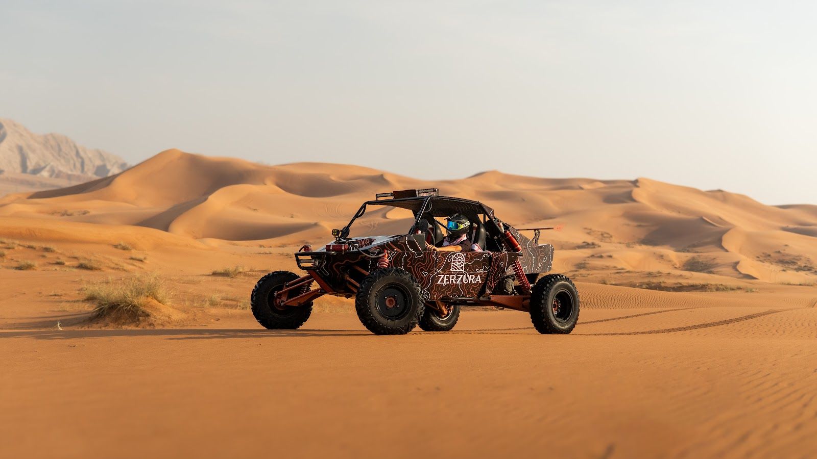A helmeted driver in a Zerzura dune buggy in the Mleiha desert