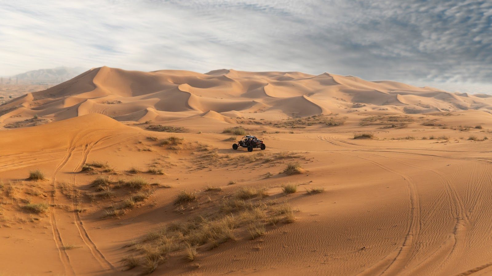 A Zerzura dune buggy crossing open desert dunes near Mleiha
