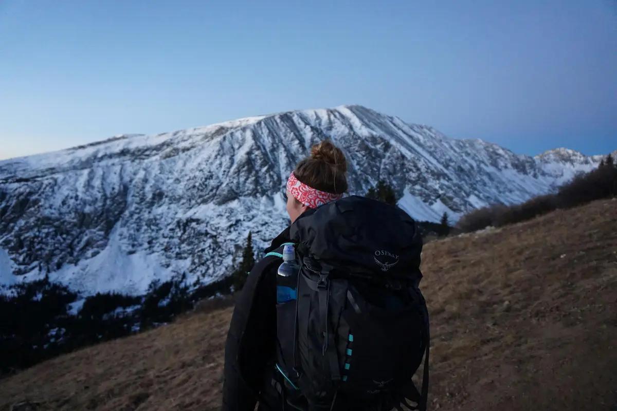 Persona en la cima de una colina mirando el amanecer, representando el éxito de superar miedos personales.