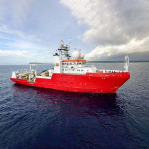 Red survey ship sailing on water