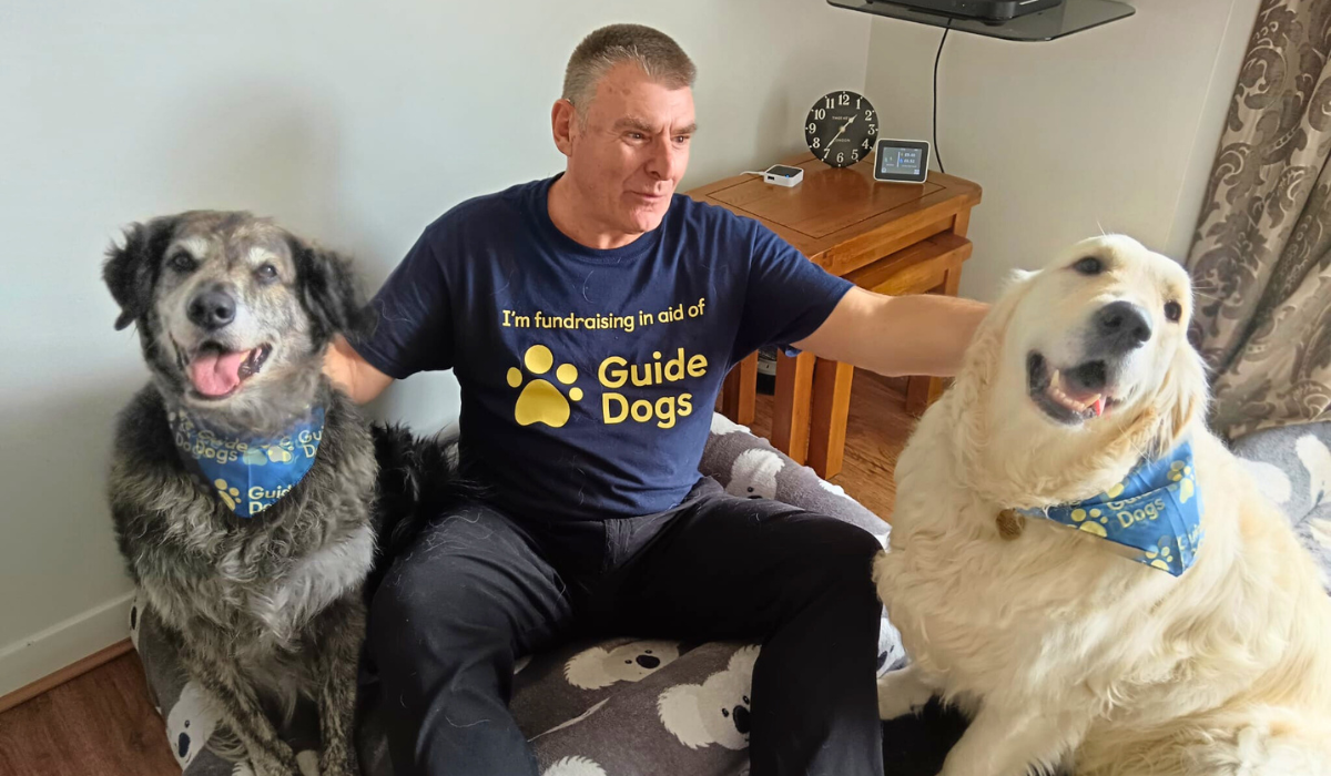 Bobby and Murphy, two gorgeous doggies, sit wearing their Guide Dogs bandanas, with Uncle Nellie sat between them wearing his Guide Dogs t-shirt