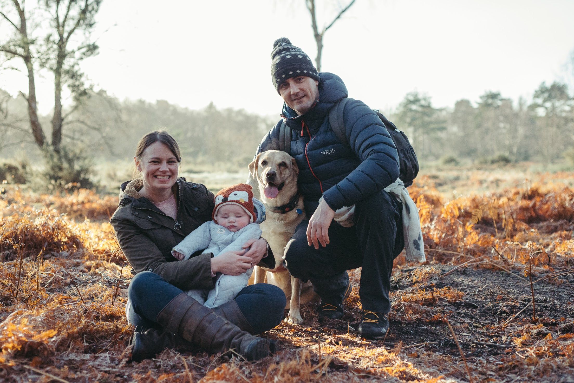 Labrador Luna poses in a Wintery landscape with a couple and a baby