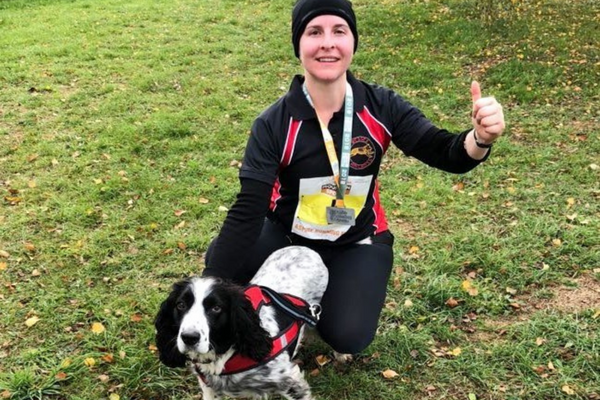 Runner, Nicola, is crouched down with a thumbs up and Sprocker, Bob, in front, they're both tired and very pleased with their race win.